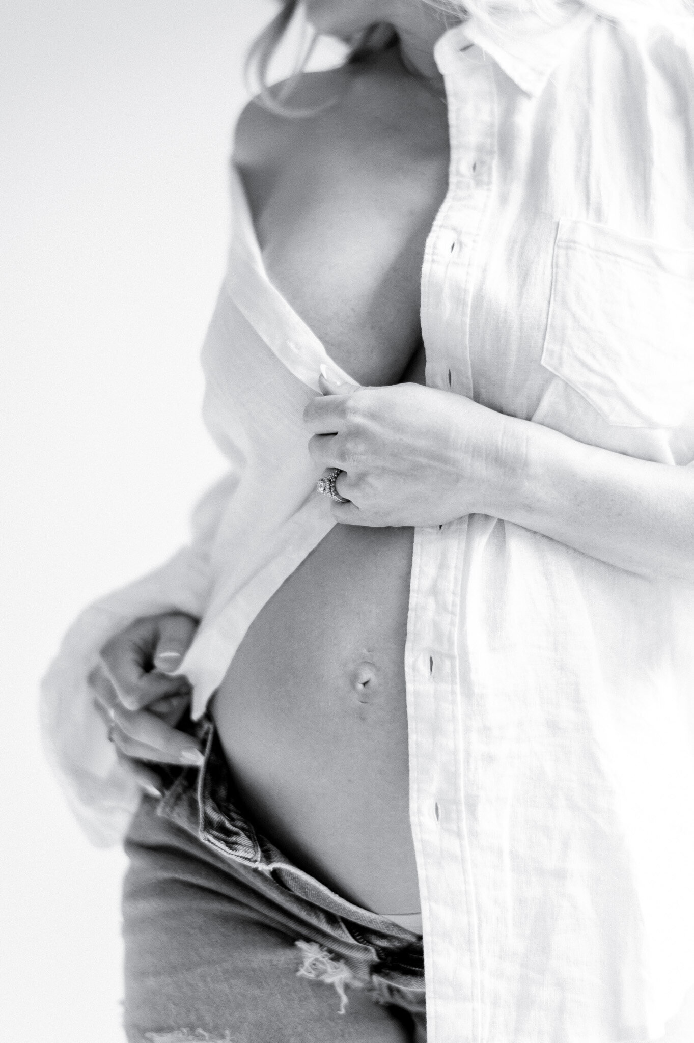 Black and white image of a pregnant stomach with a white shirt barely covering her stomach