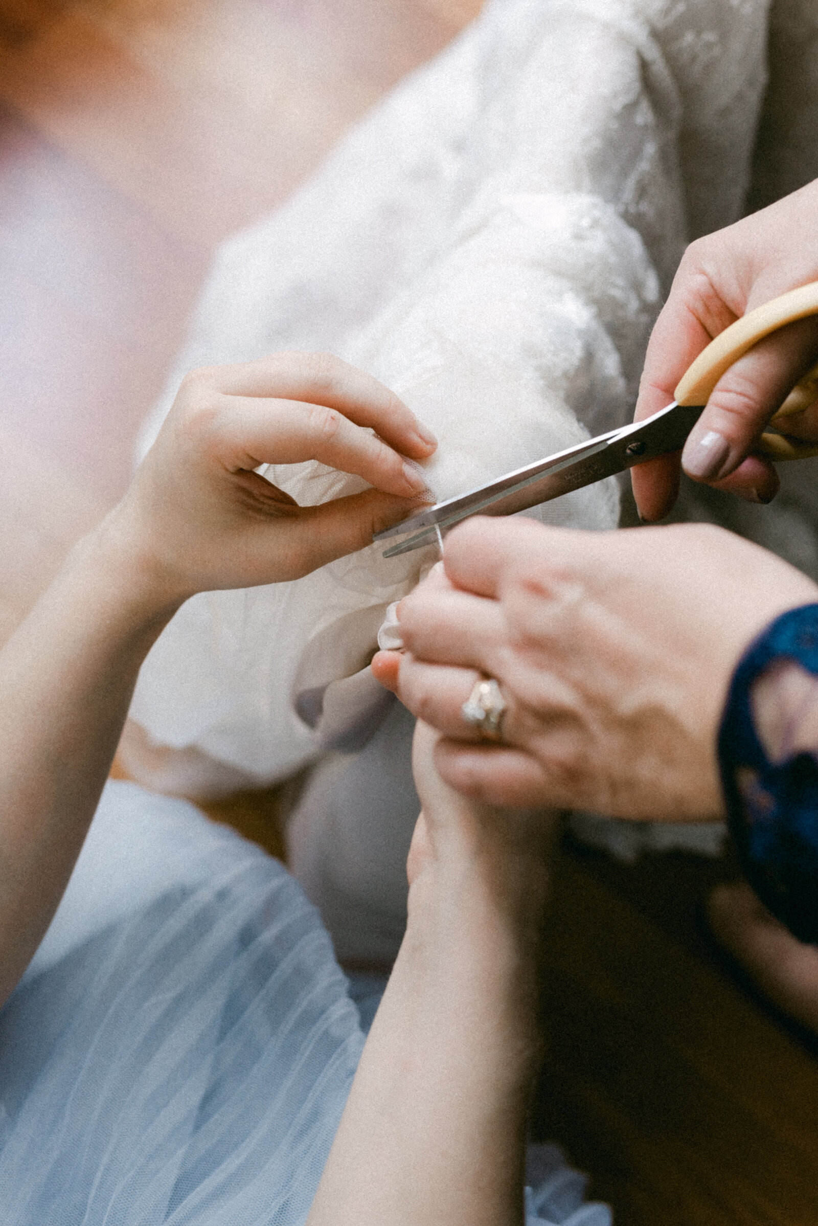 Bride's mother is cutting a string on the wedding dress in an image photographed by wedding photographer Hannika Gabrielsson.
