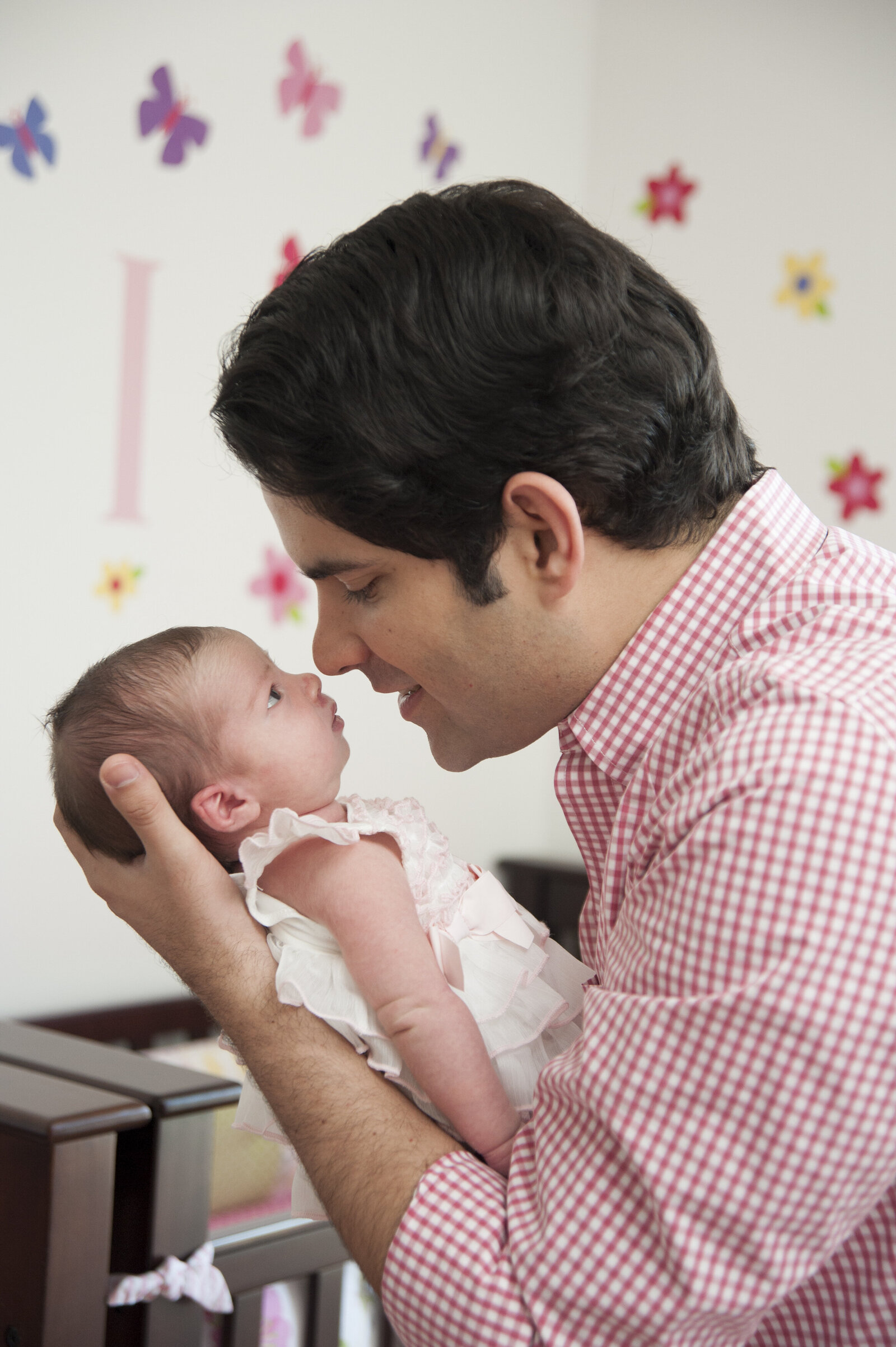 A parent holding up their newborn so they are nose to nose 