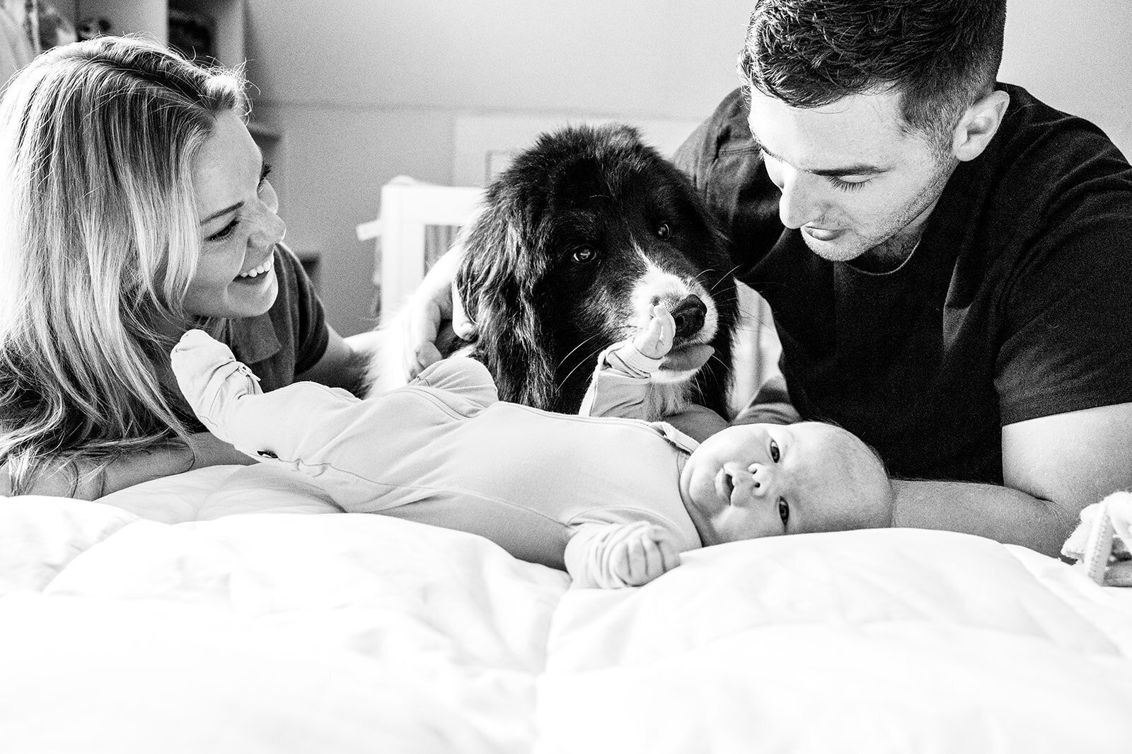 Parents tending to baby in a cozy attic nursery, with their dog resting nearby on the bedroom floor