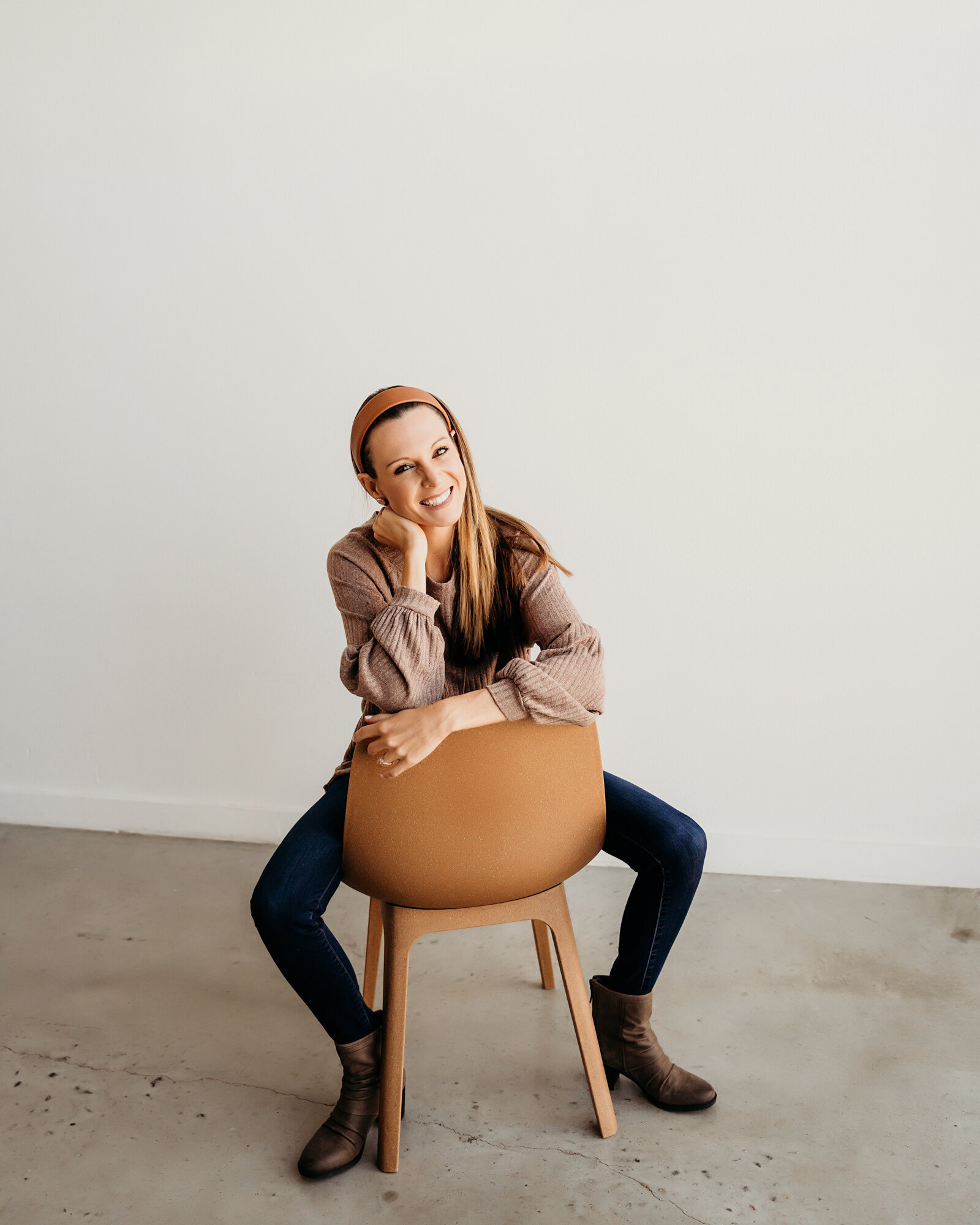 Branding Photographer, a woman sits backwards in a chair, her elbow on its back, she smiles