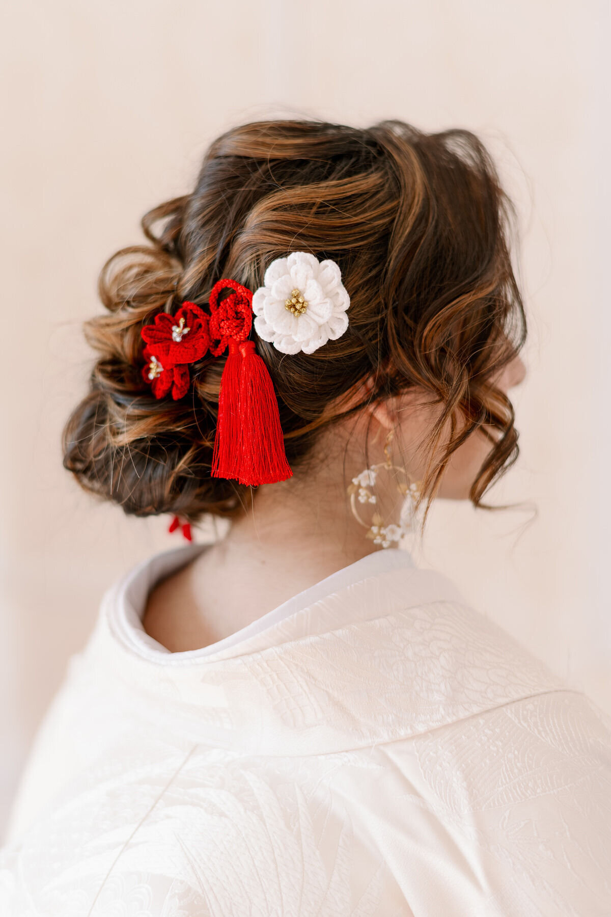 Back view of bride in pure white shiromuku wedding kimono rental with delicate red and white floral hair accessories, studio session in Los Angeles California | 白無垢花嫁の後ろ姿。赤と白の髪飾りが際立つロサンゼルス カリフォルニアのスタジオ和装ウェディング着物レンタル。