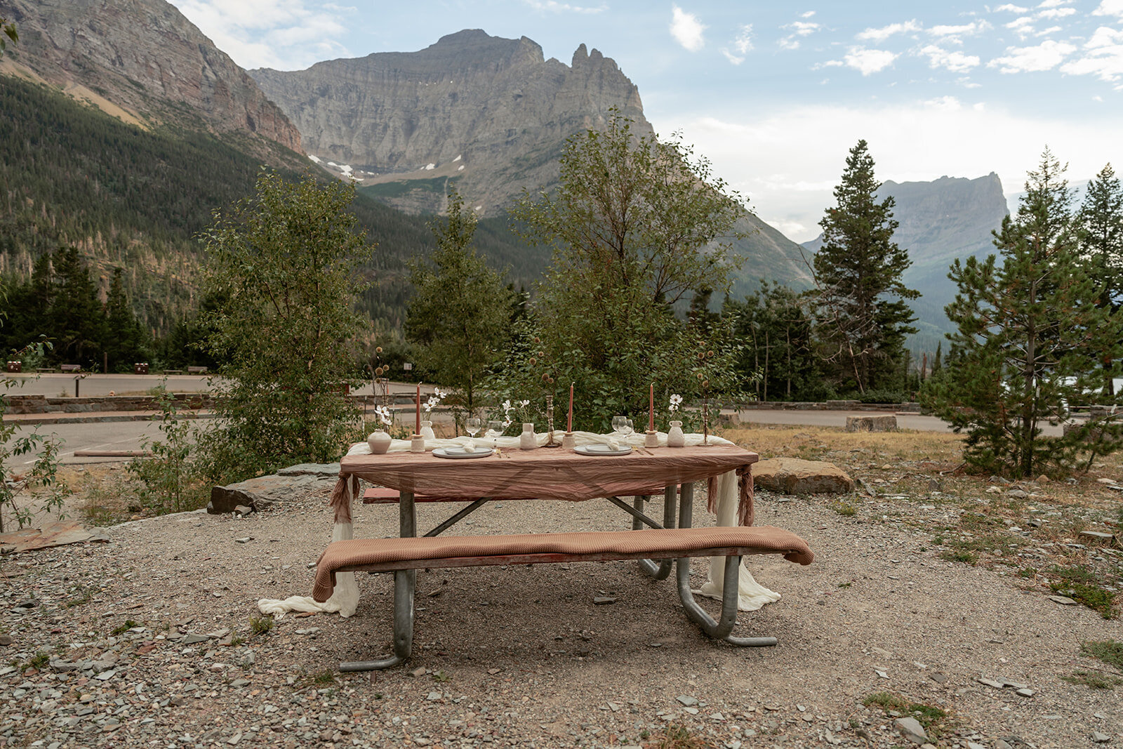 A simple elopement picnic table styled with earthy linens and taper candles, set against the mountains for a relaxed, intimate post-ceremony meal.