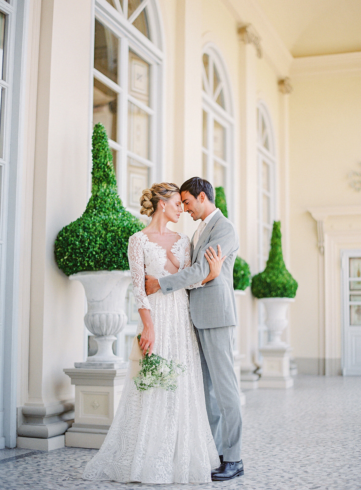 Bride and groom on the veranda of the villa, holding each other. Photographed by Amy Mulder Photography.