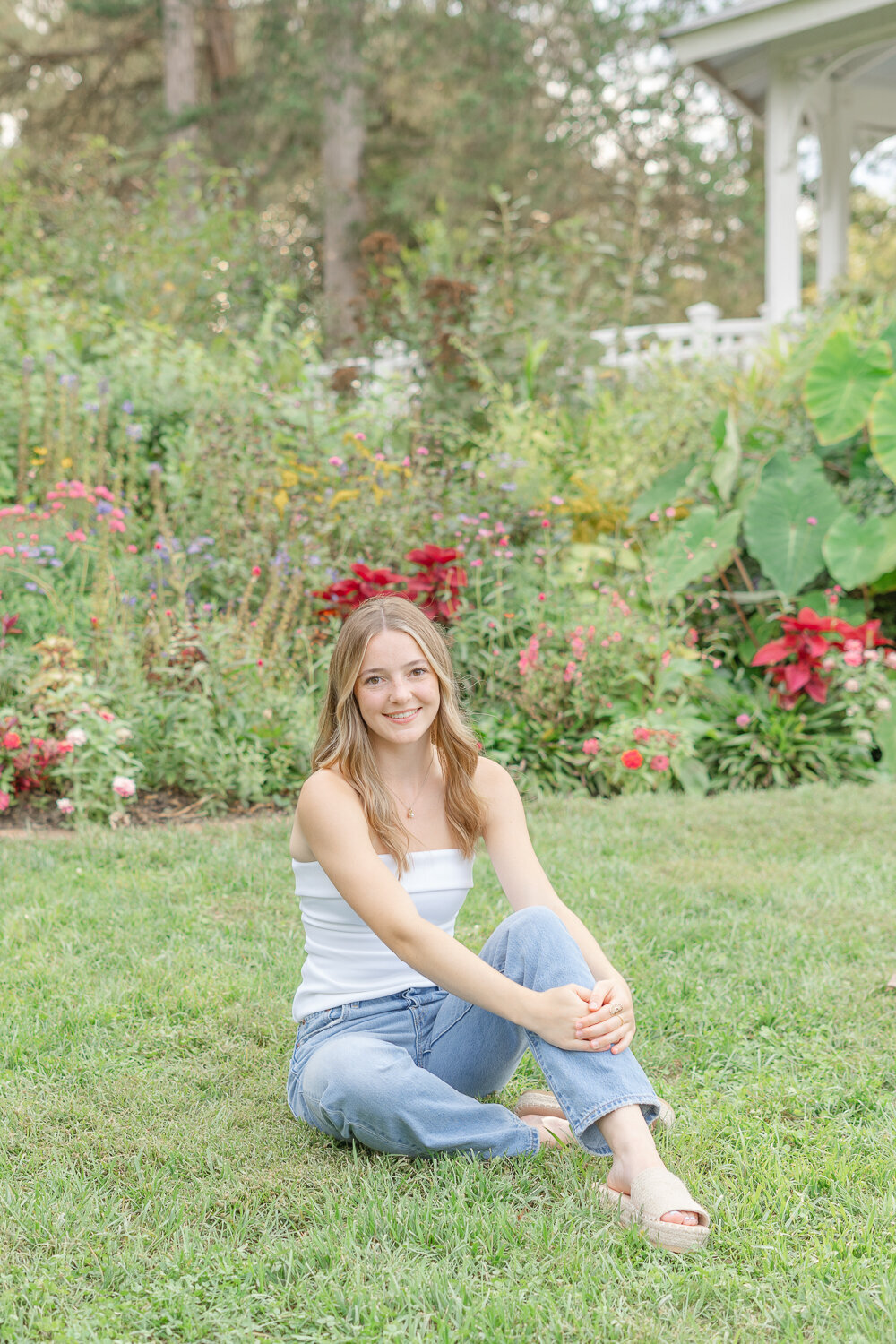 high school girl sitting in front of flowers taken by DMV senior photographer