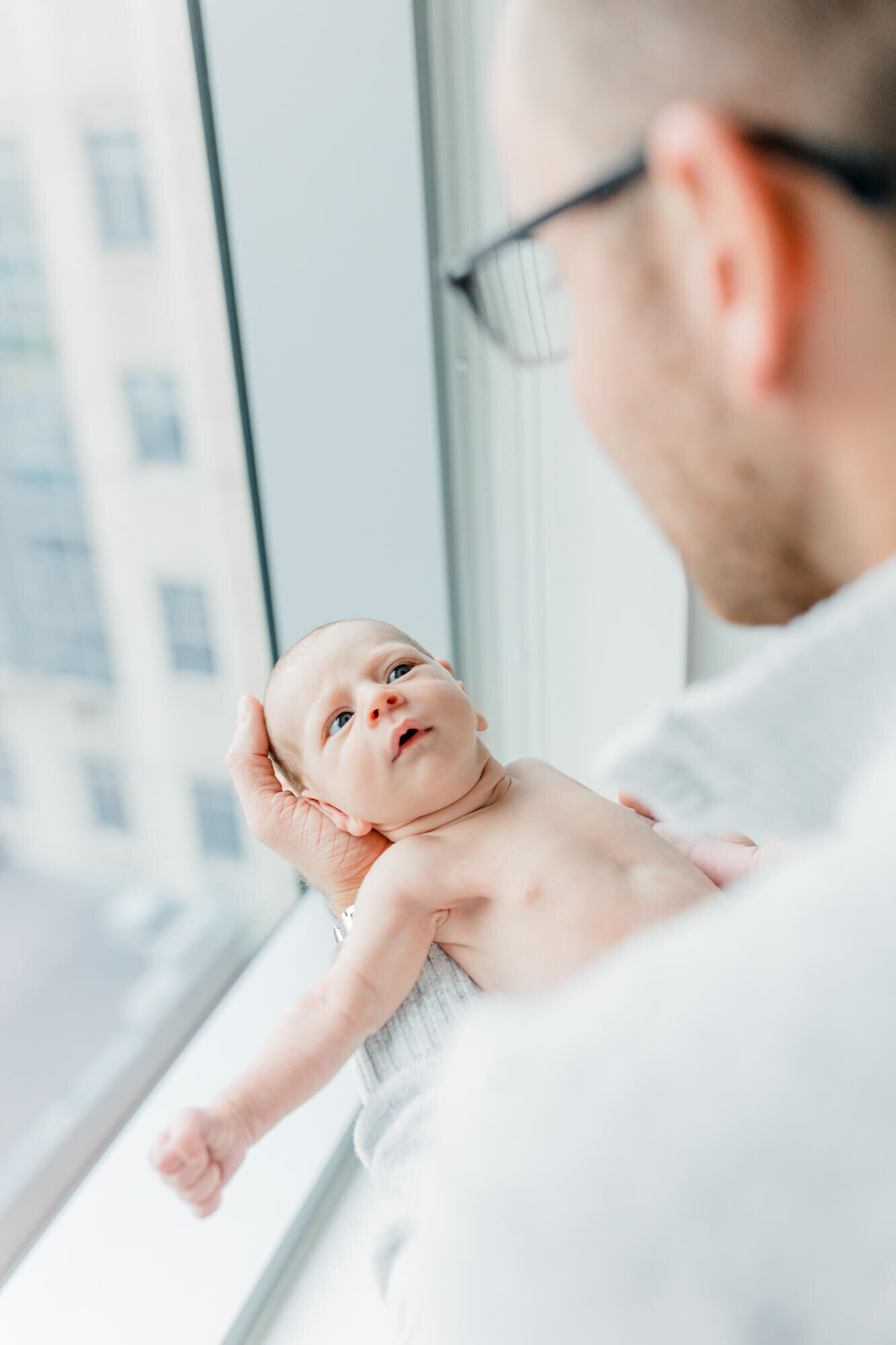 Taken from behind dad's shoulder, baby stares up at his dad