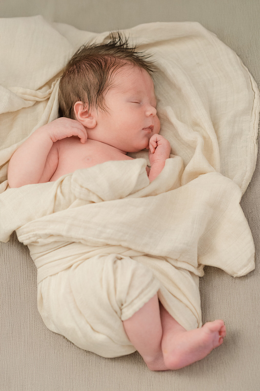 newborn baby boy wrapped in a cream colored blanket sleeping with a lot of dark hair by york pa photographer