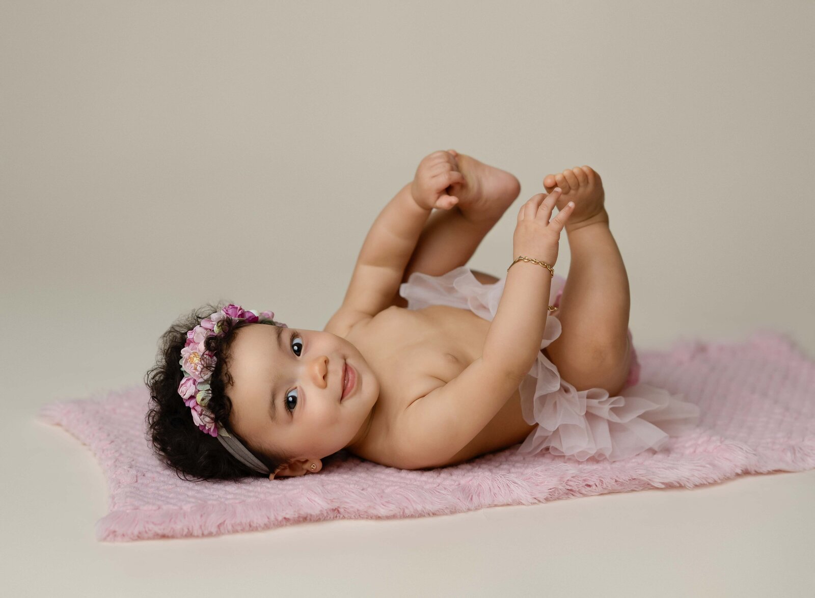 Milestone photo of baby girl on back, grabbing her toes. Baby milestone photo taken by Jenni Nikki Photography in Atlanta, GA. 