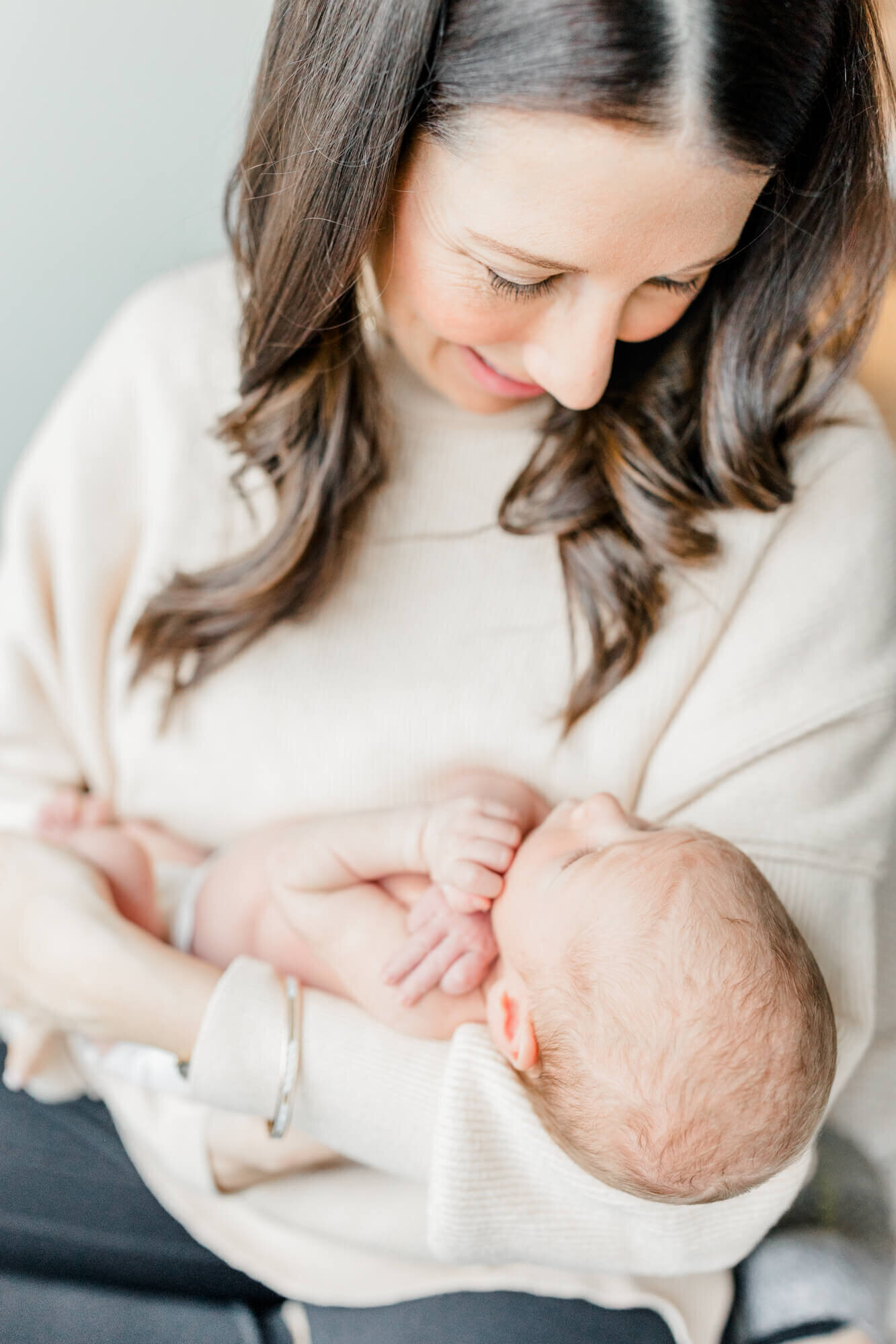 Mom smiles down at her newborn baby, who is looking up at her