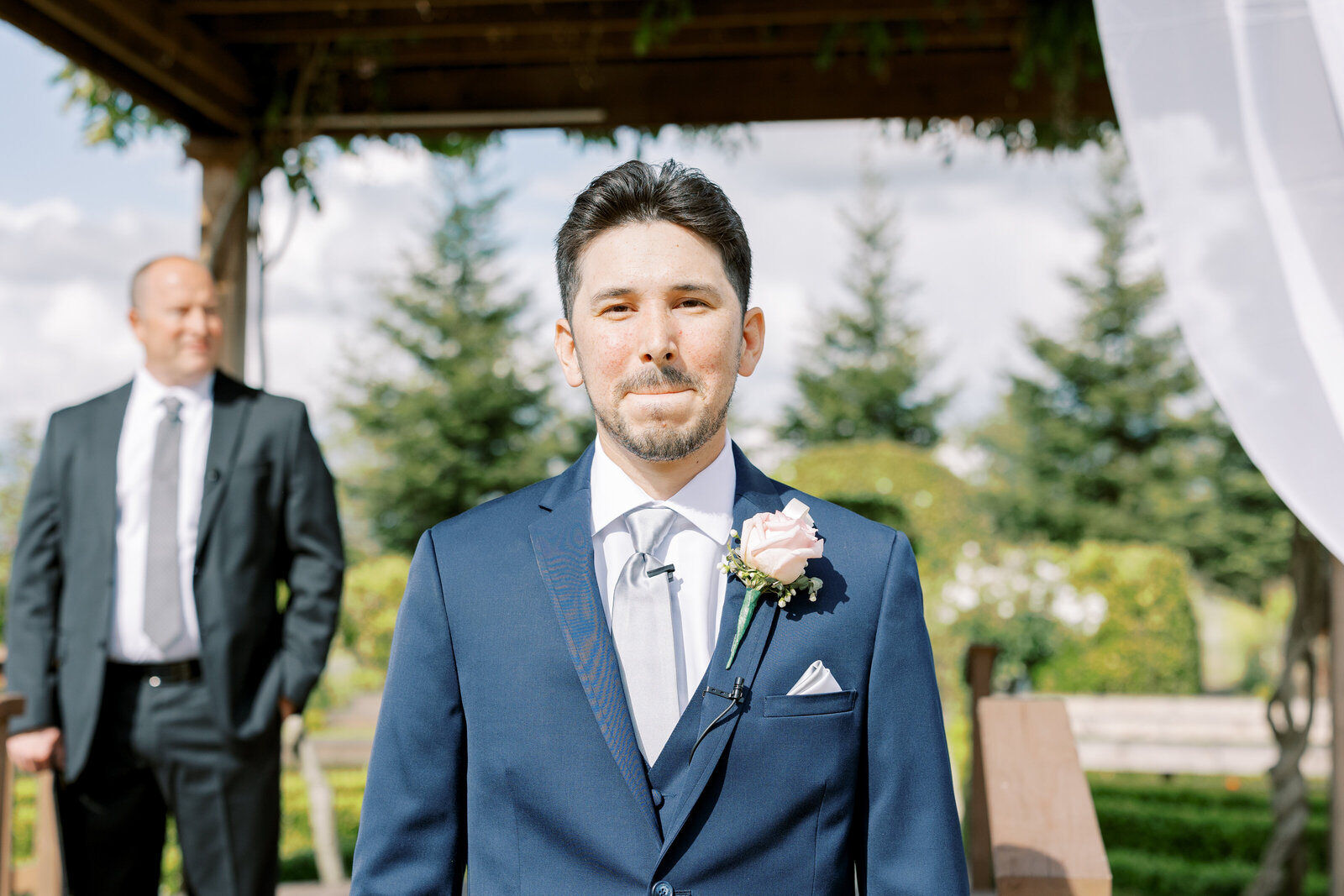 sacramento wedding photographer captures groom waiting for his bride during their outdoor wedding reception while wearing a blue suit