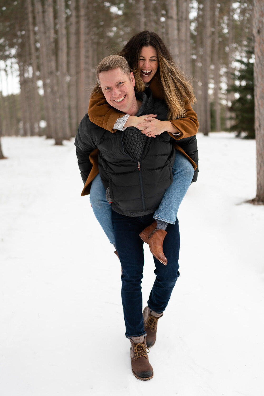 Woman rides on man's back in the snow in Anoka, Minnesota.