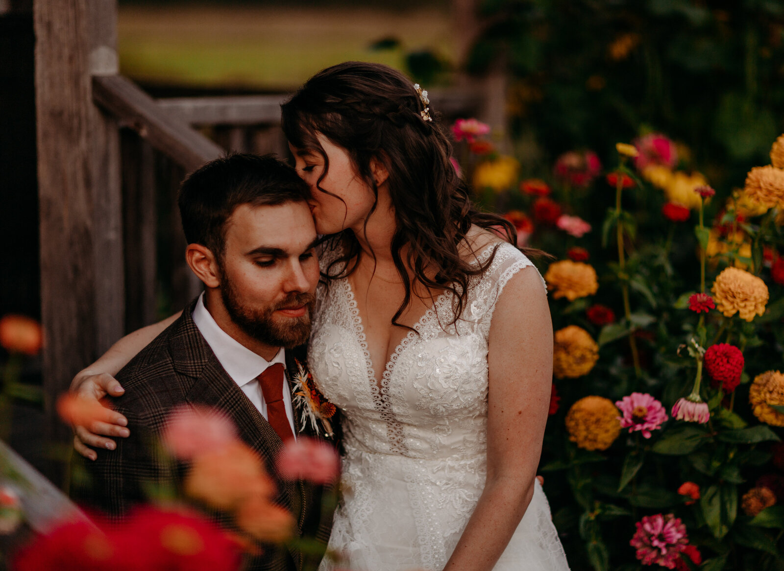 Fall wedding at The Saltbox Barn on Fir Island in Mount Vernon, WA. Couple in wedding attire sitting amongst flowers.