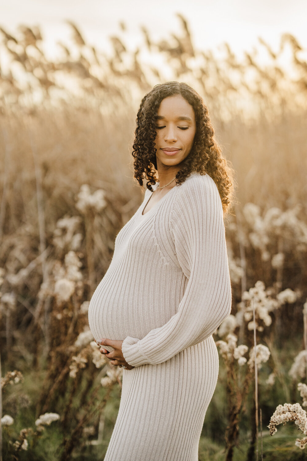 pregnant mom in cream dress stands among cattails for boston pregnancy photos