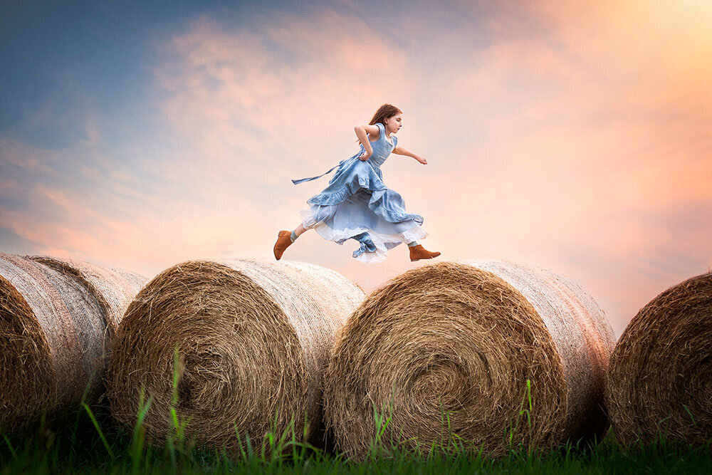 girl-blue-dress-hay-jumping-farm-best-life-cotton-candy-sky-fine-art-unique