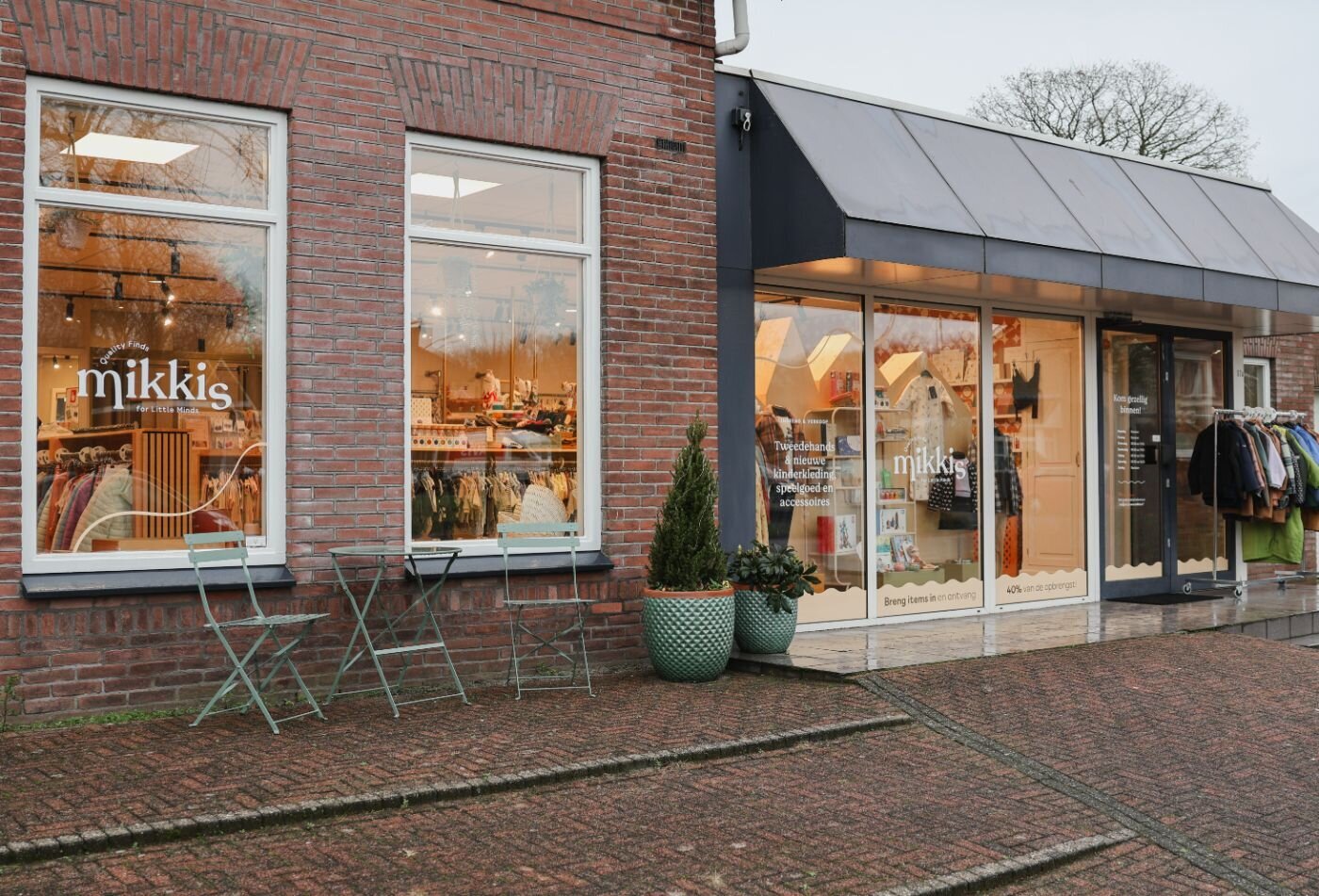 De buitenkant van een winkelpand met een bakstenen gevel en de naam 'Mikkis' op de ramen.