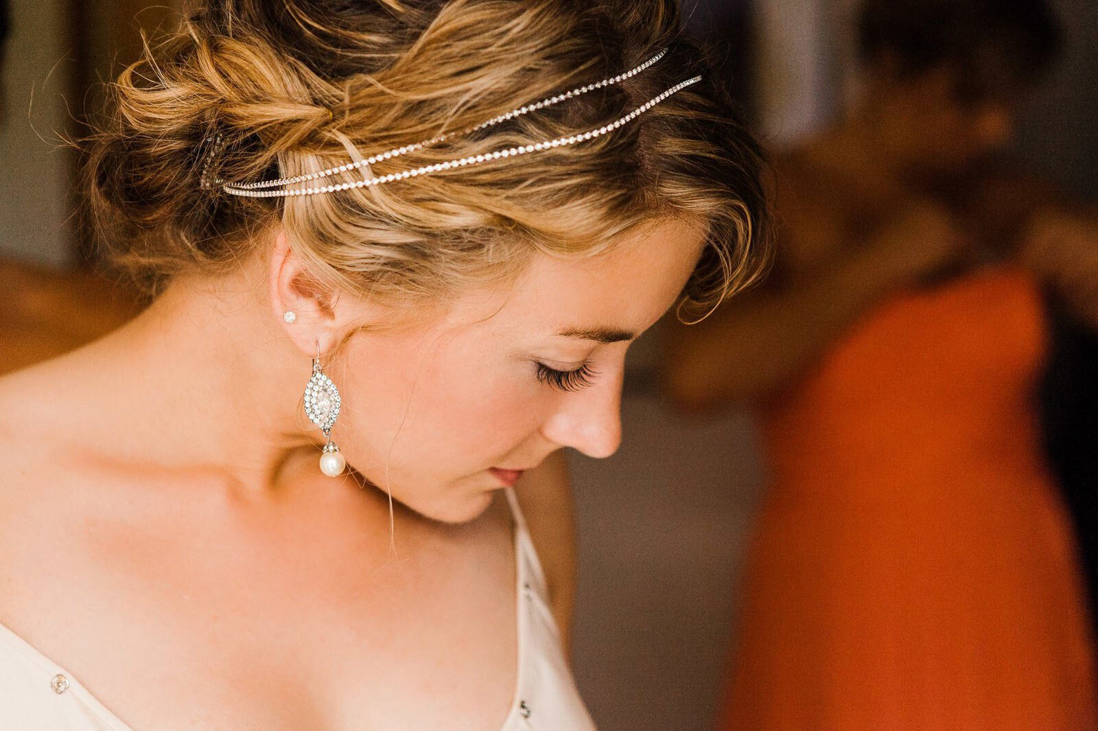 a bride wearing a beaded headband and crystal earrings looking over her shoulder