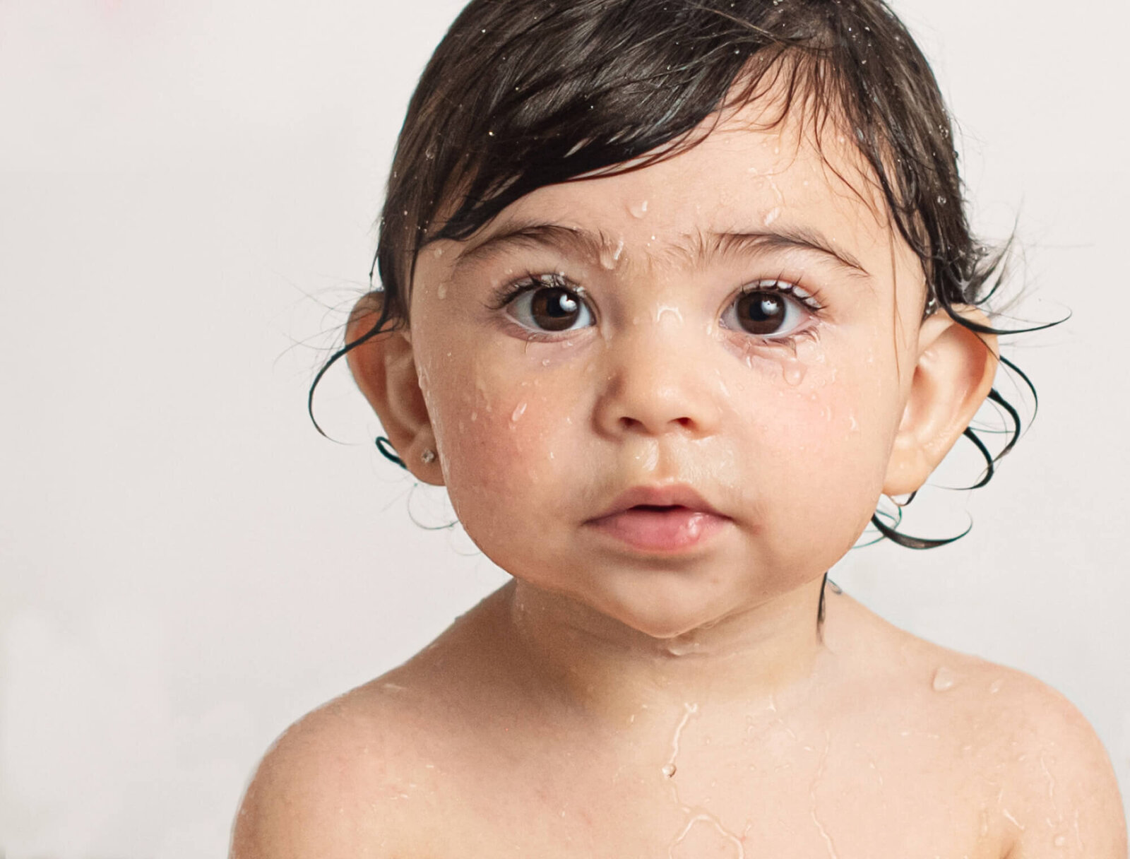 One year old girl with water droplets on face close up