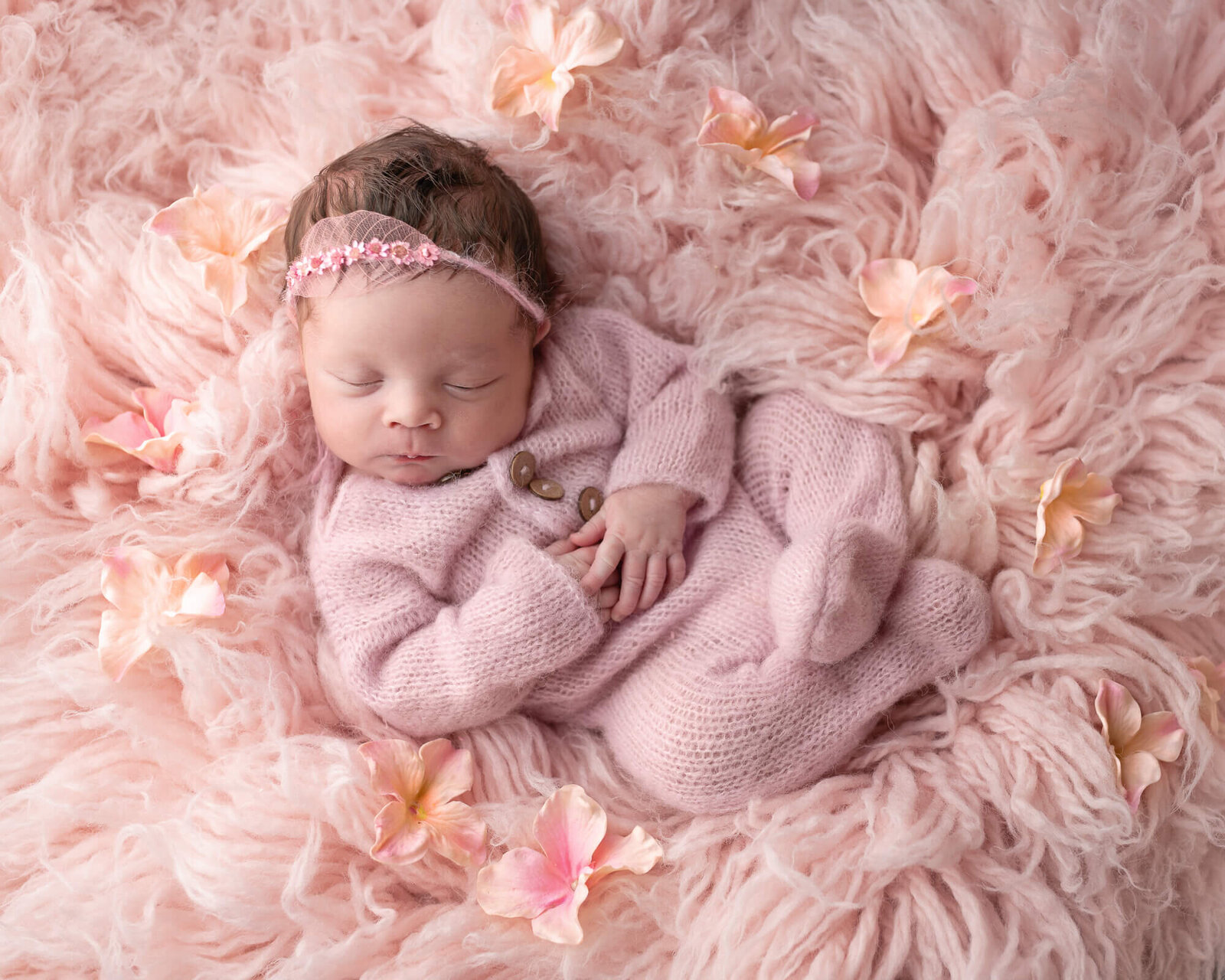 baby picture of girl snuggled up on pink fluffy rug