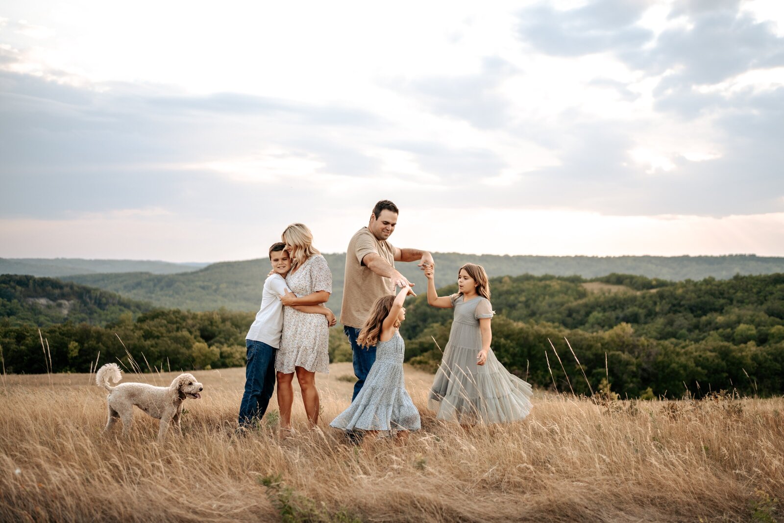 Family dancing and hugging on hilltop for family photography