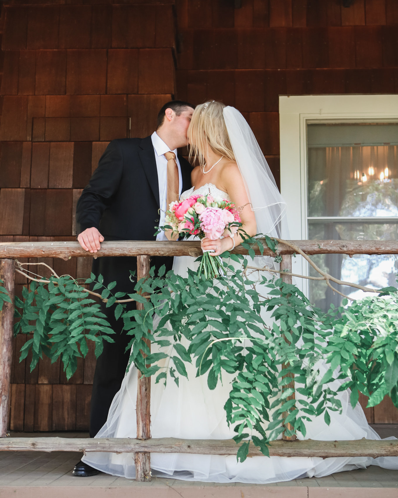Bride and groom kiss in front of beautiful rustic wedding venue