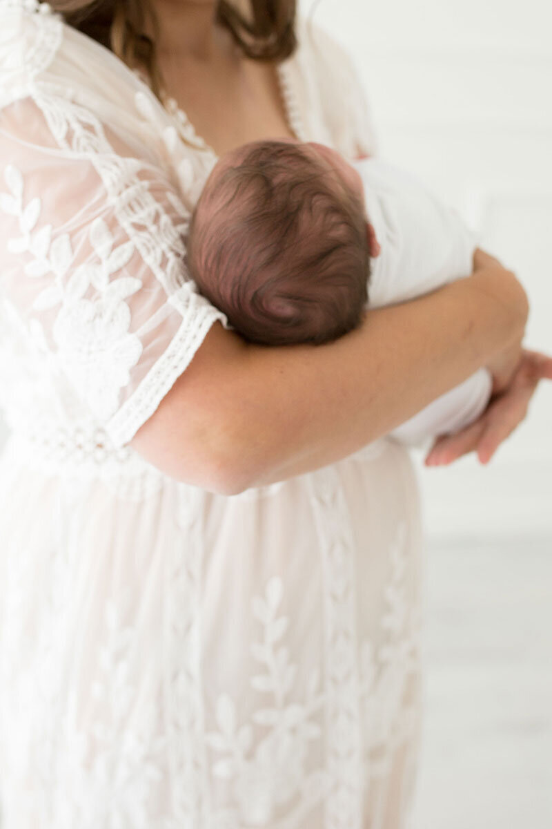 Neugeborenenfotografie: Mama hält Baby im Arm.