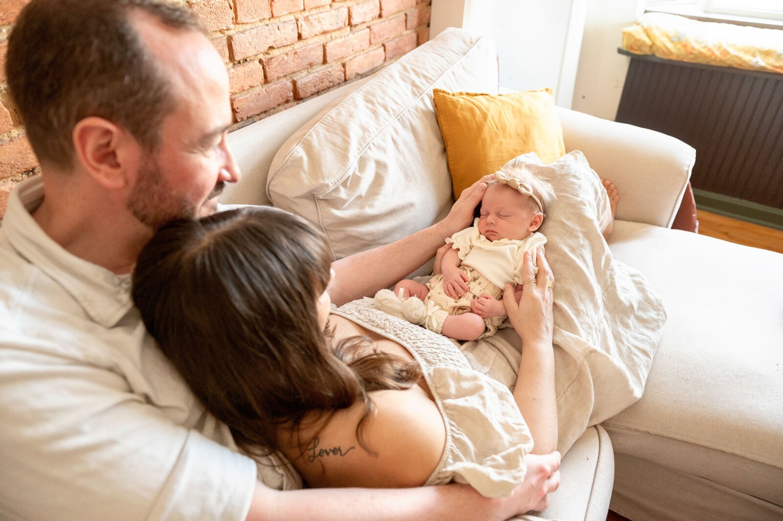 husband and wife on couch in their baltimore home holding newborn baby girl
