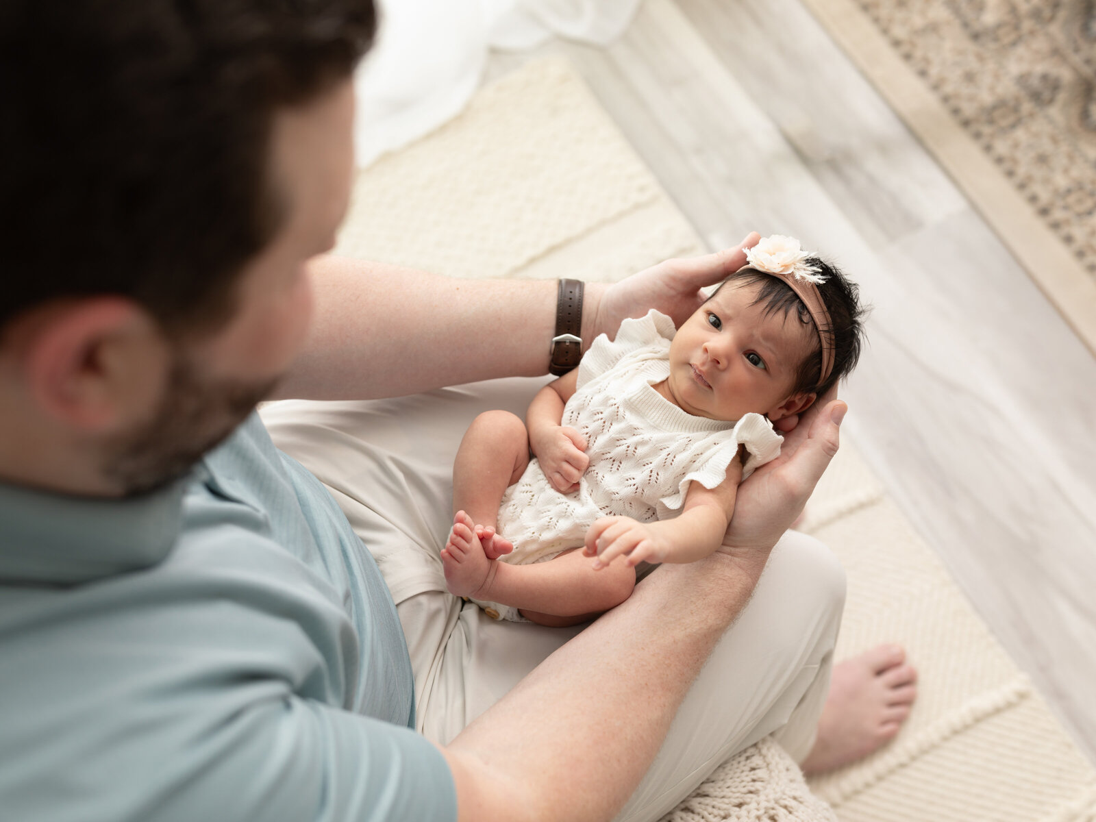 dad holding newborn baby girl in white onesie for newborn photoshoot cleveland newborn photographer