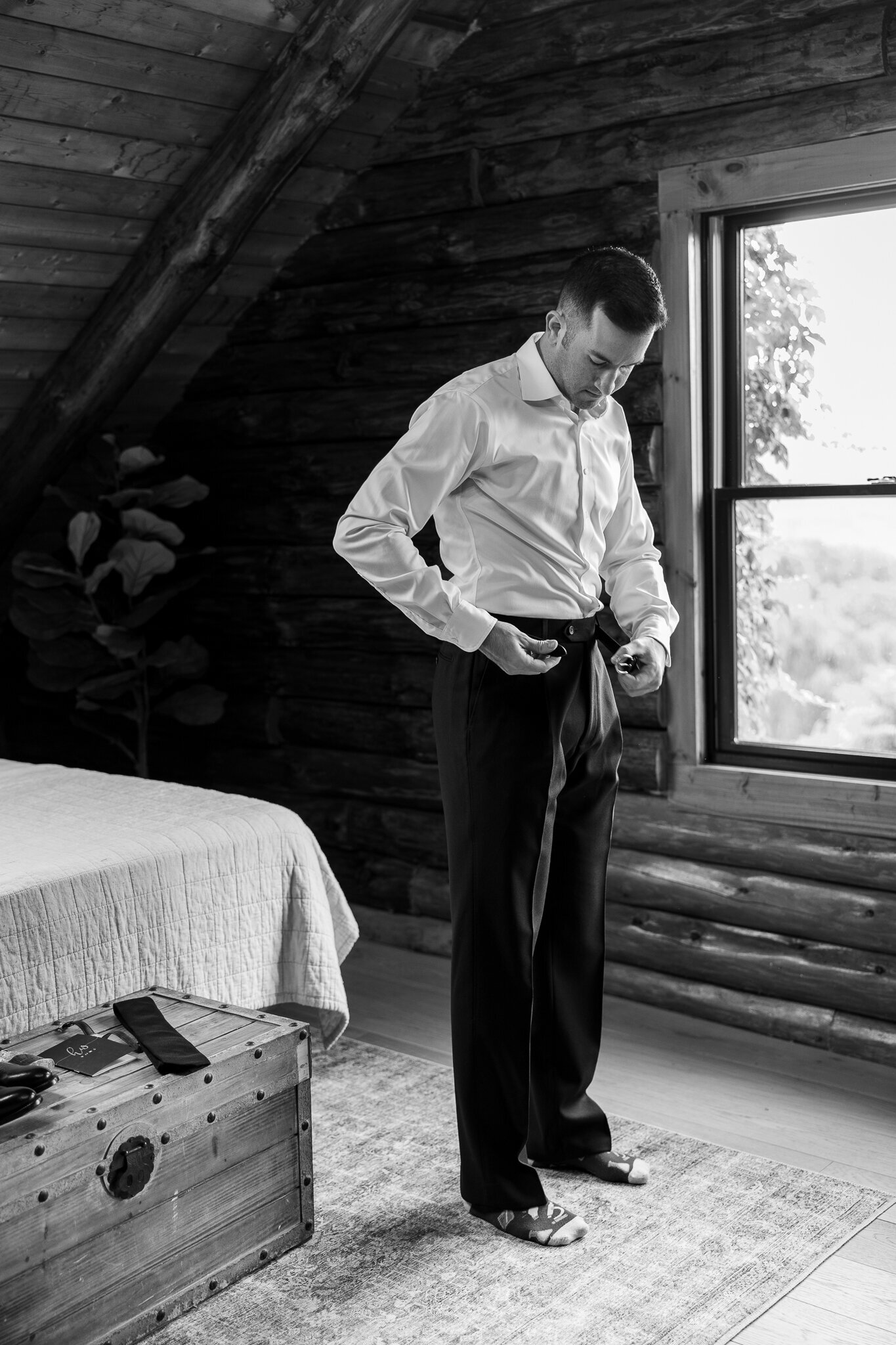 Groom putting on belt while getting dressed for wedding at SkyView Golf Club