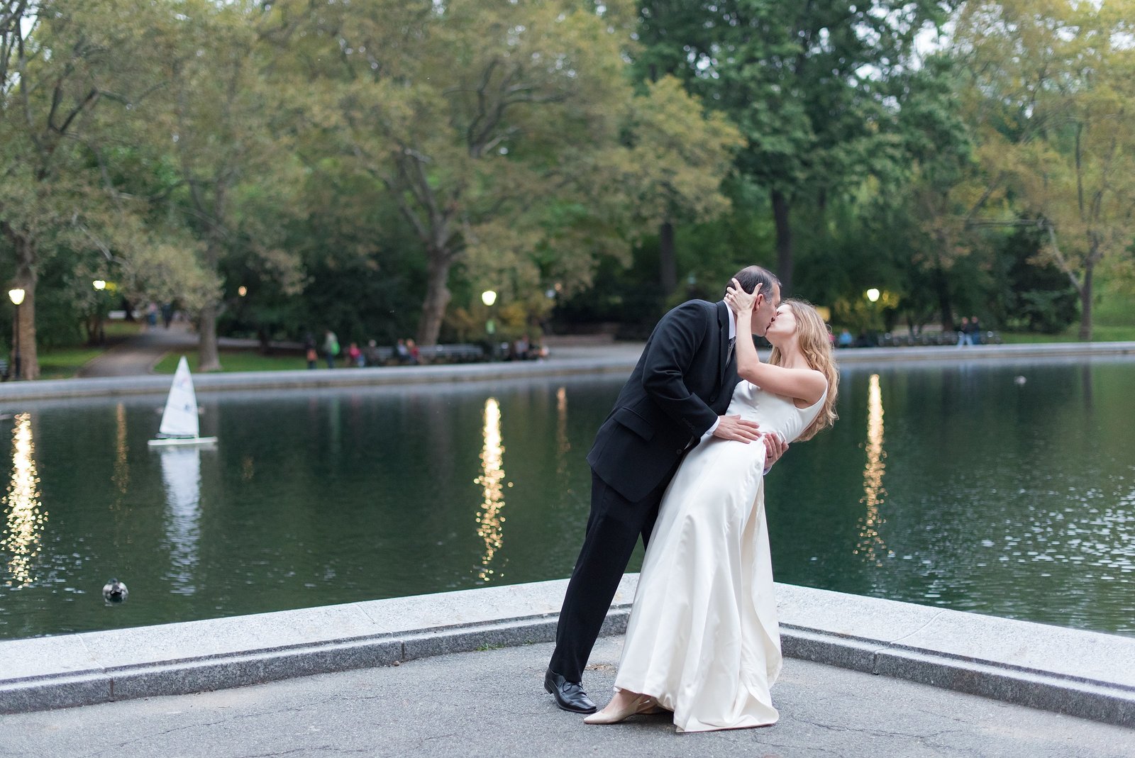 Groom dipping and Kissing Bride in front of pond with little boats at Conservatory Water in Central Park, New York City Photo