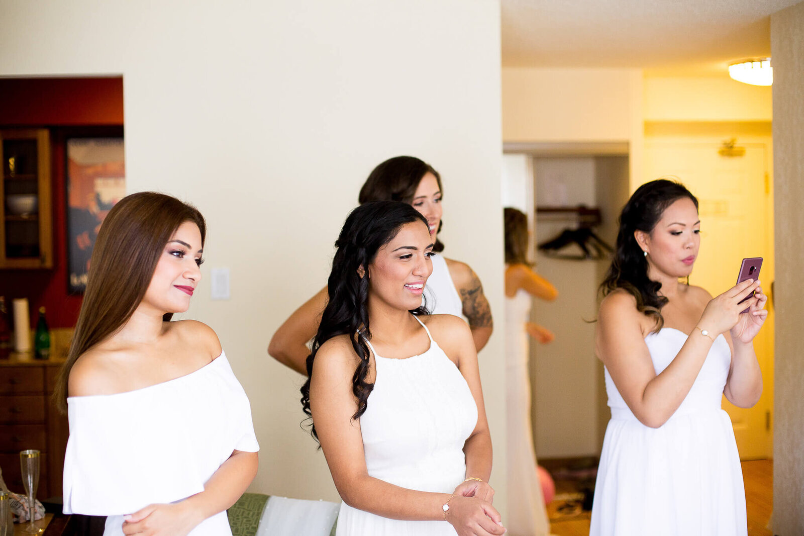 Bridesmaids looking on as bride gets ready.