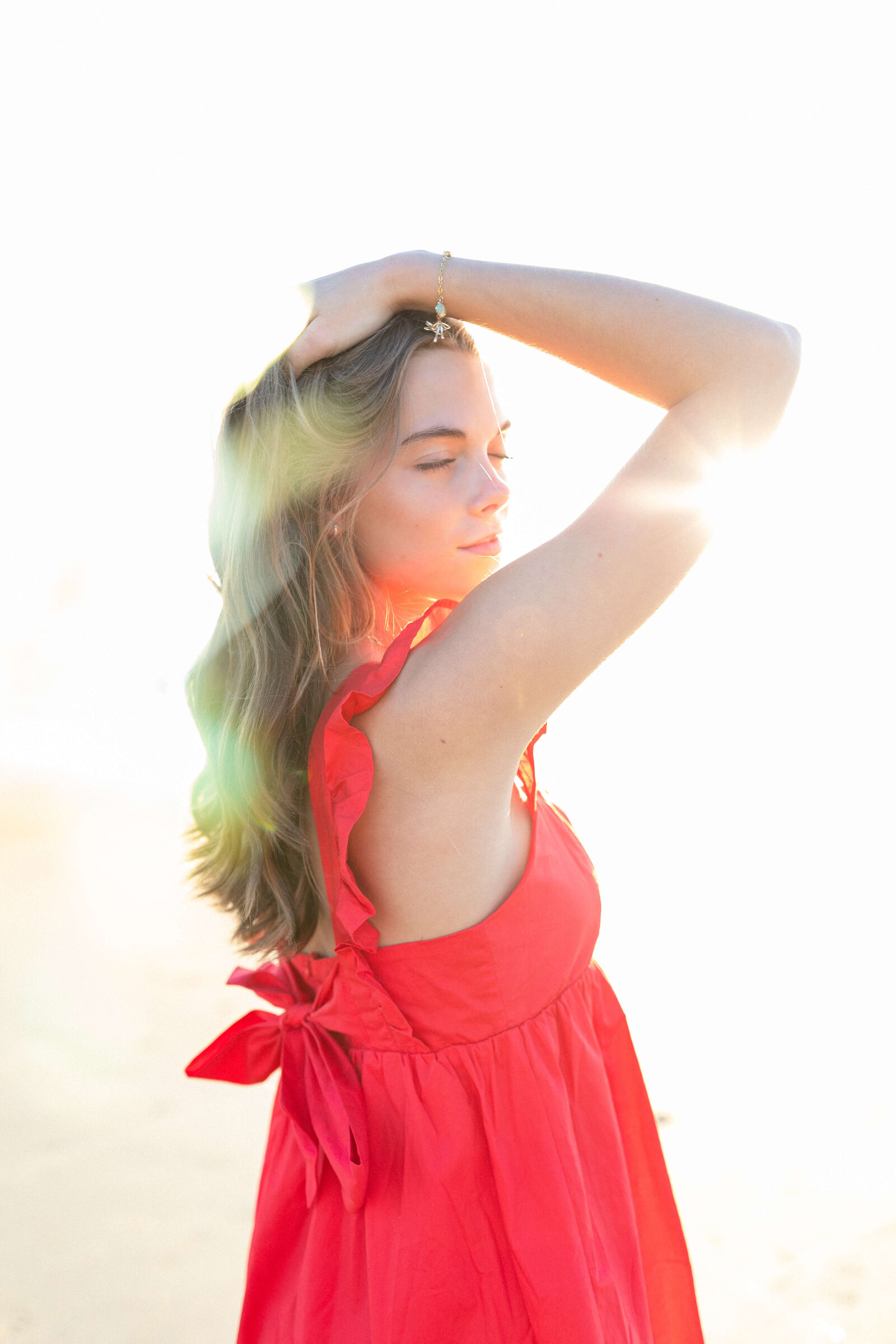 brunette posing in a red dress for senior pictures