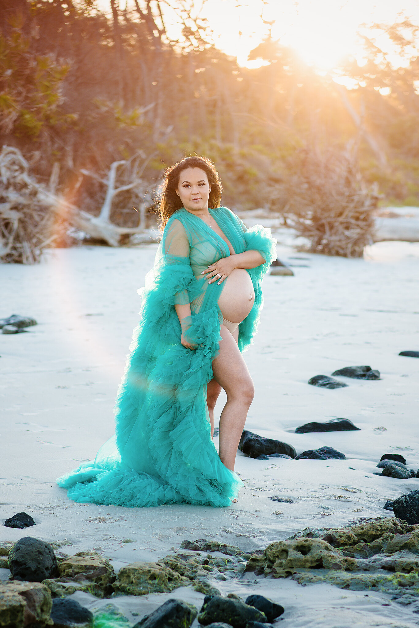 Beautiful expectant mother in frilly green robe with belly exposed at Black Rock Beach in FL.