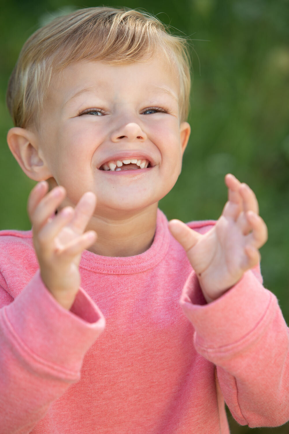 A young boy wearing a pink shirt is clapping his hands