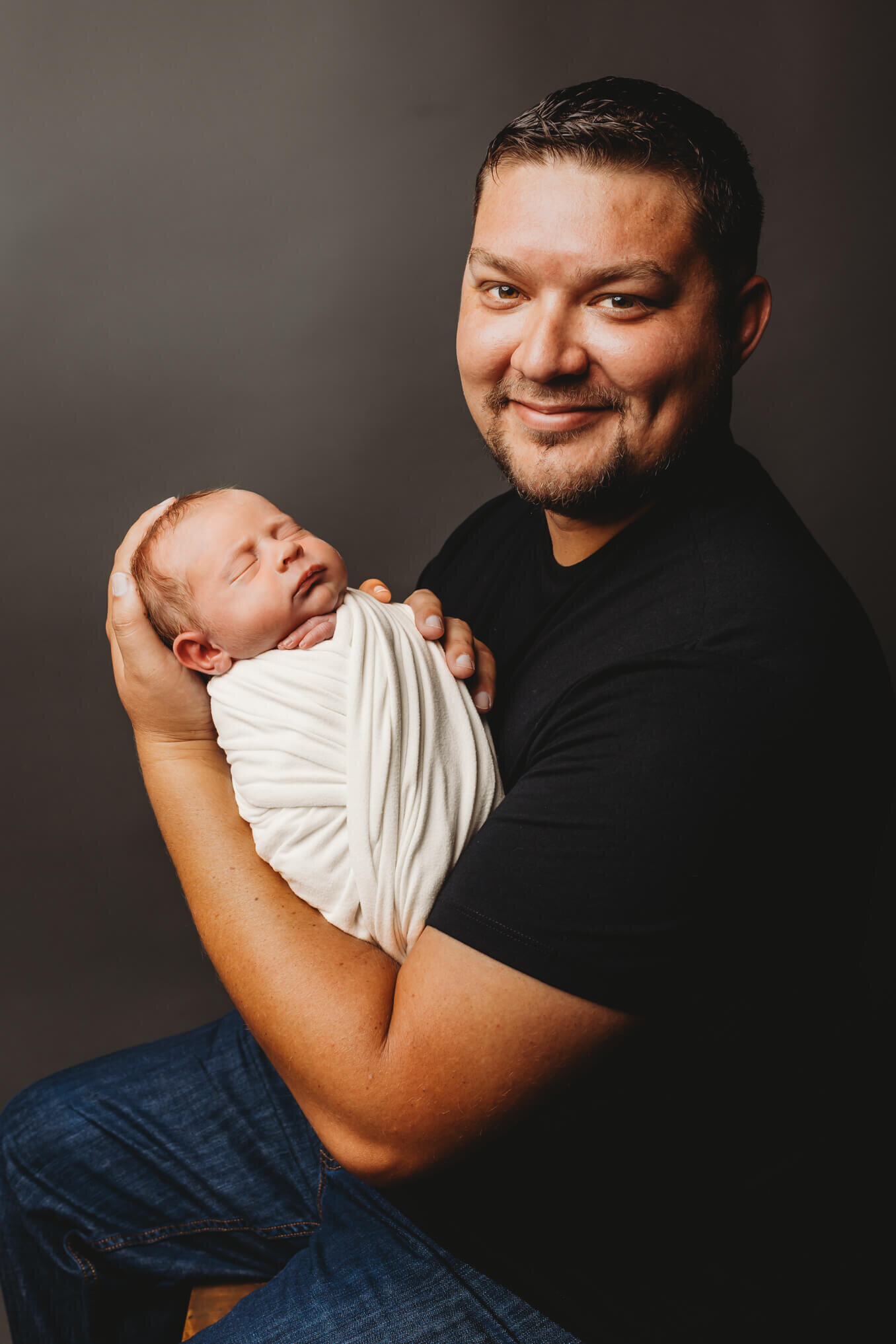 Dad holding swaddled baby in a football hold