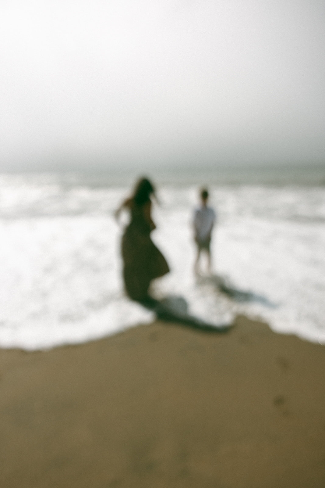 out of focus photo of mom and son standing in the pacific ocean