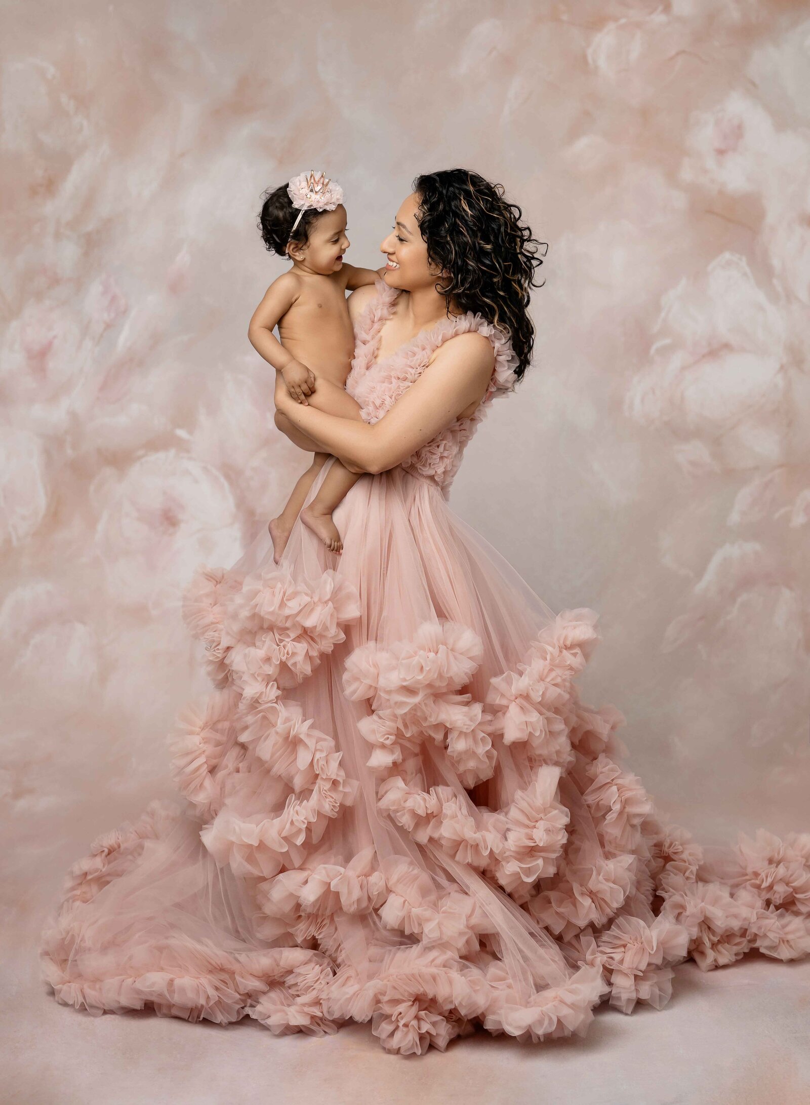 Mom in pink tulle dress and holding naked baby girl, looking at each other and smiling. Photographed in Atlanta by Jenni Nikki Photography.