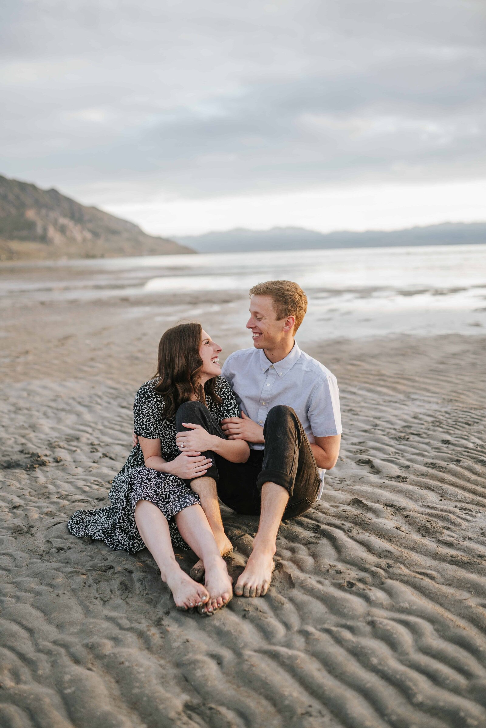 Sacramento Wedding Photographer captures couple sitting on sand by the beach during beach engagements