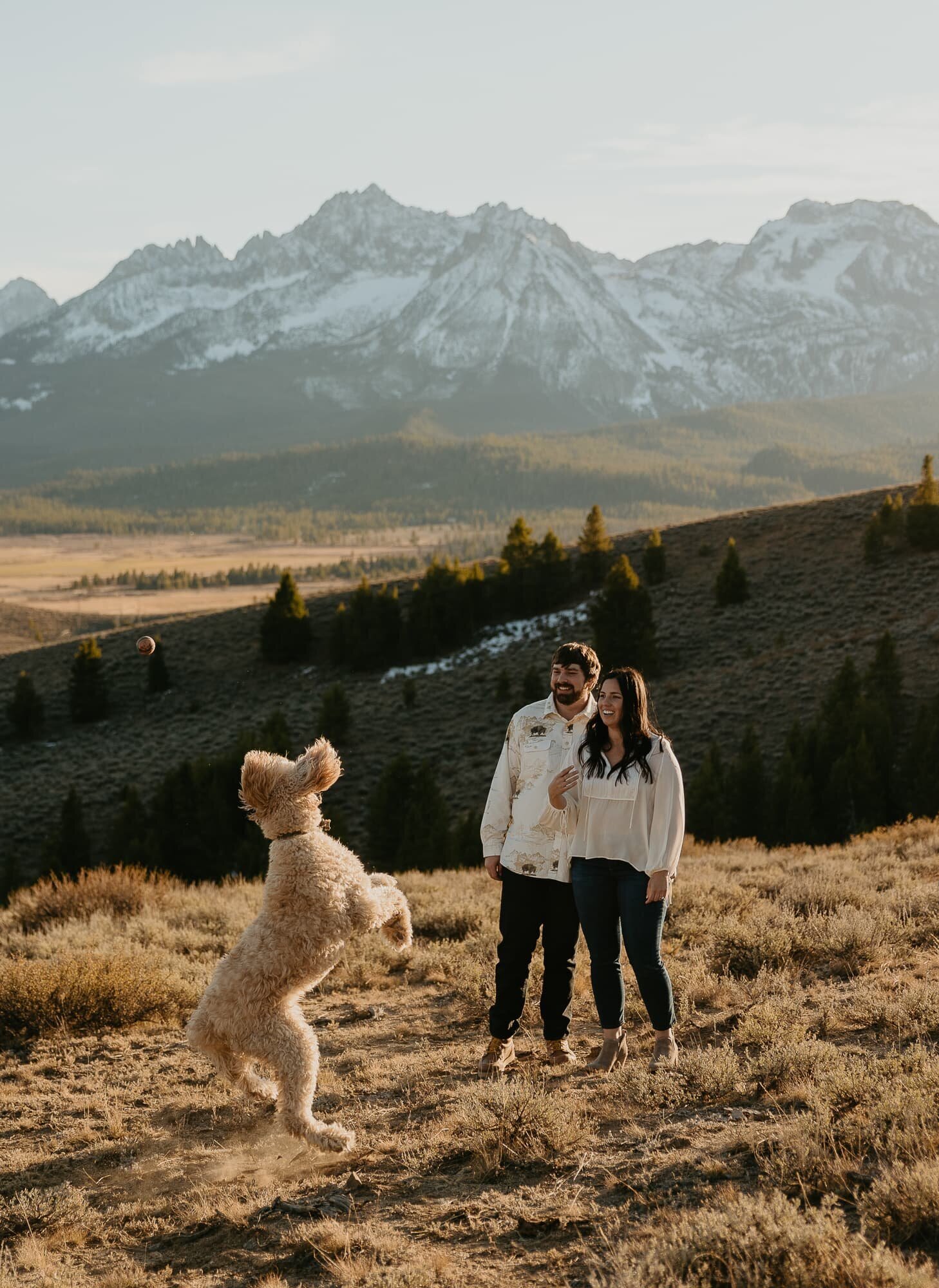 A couple playing with their dog during and engagement photo session in Stanley, Idaho