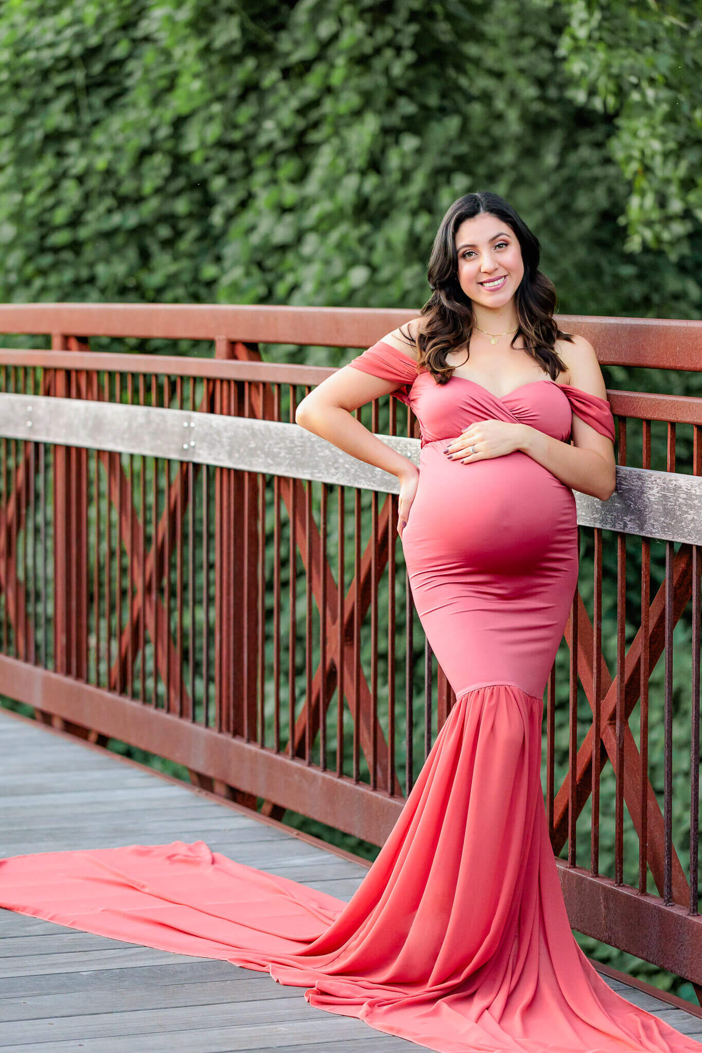 A pregnant woman posing on a bridge during her Woodbridge maternity photo session.