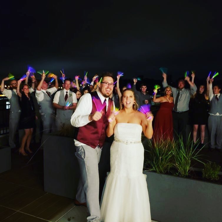 Bride and groom lighting sparklers at the end of a night in front of wedding guests