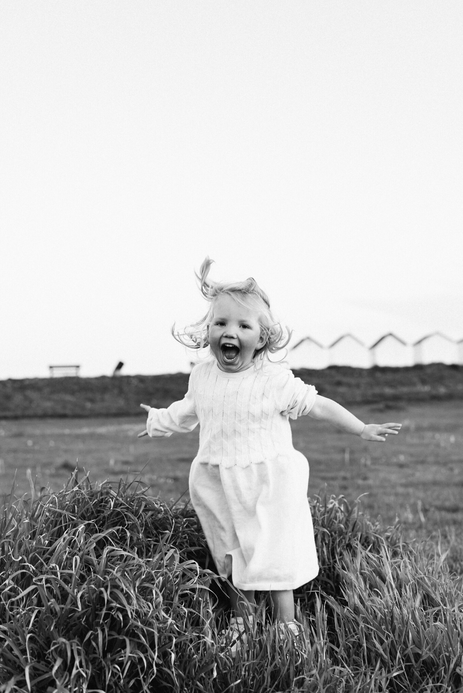 Little girl jumping in the air at the beach at a family photoshoot in West Sussex
