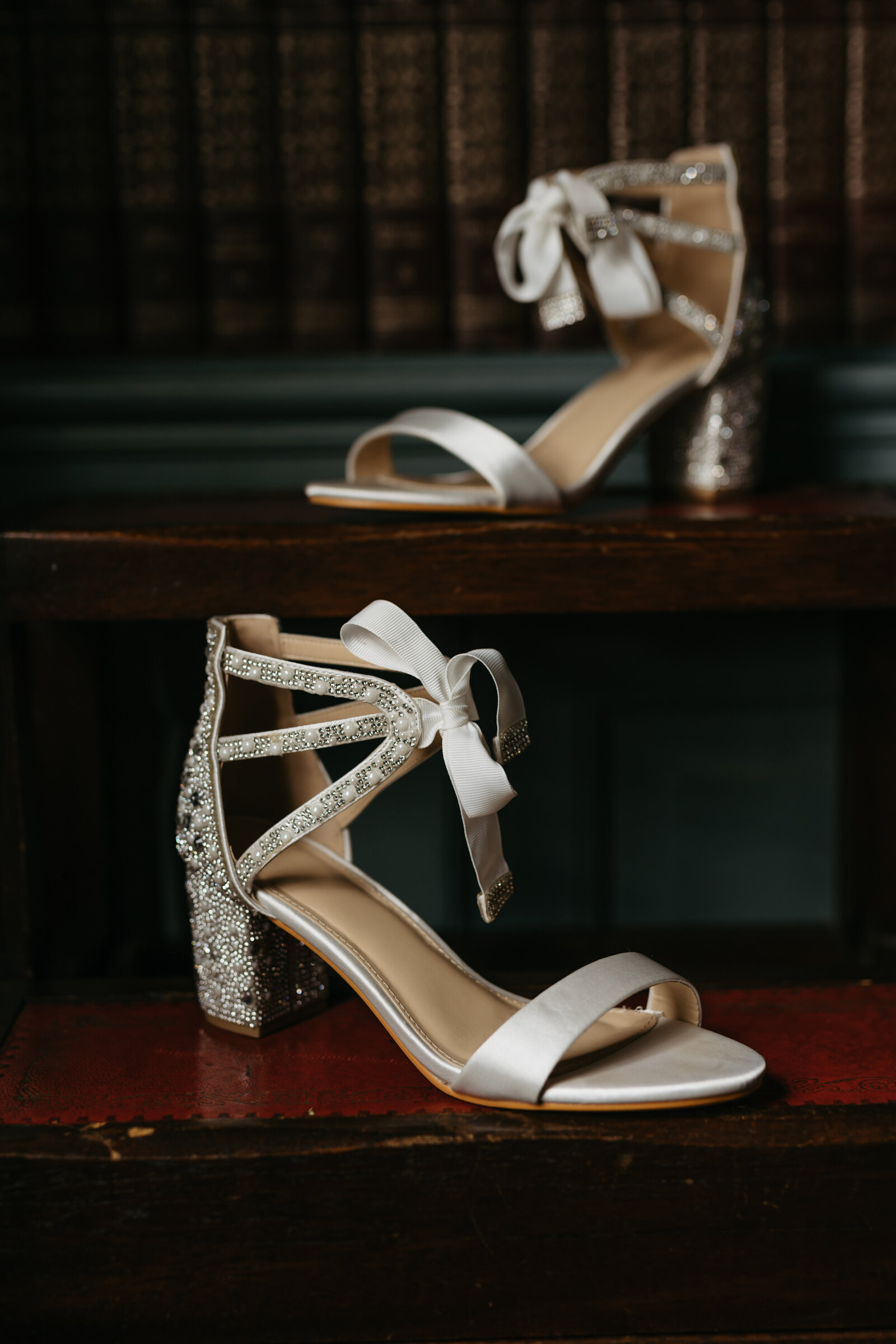 White wedding shoes sit in front of a bookshelf in a library