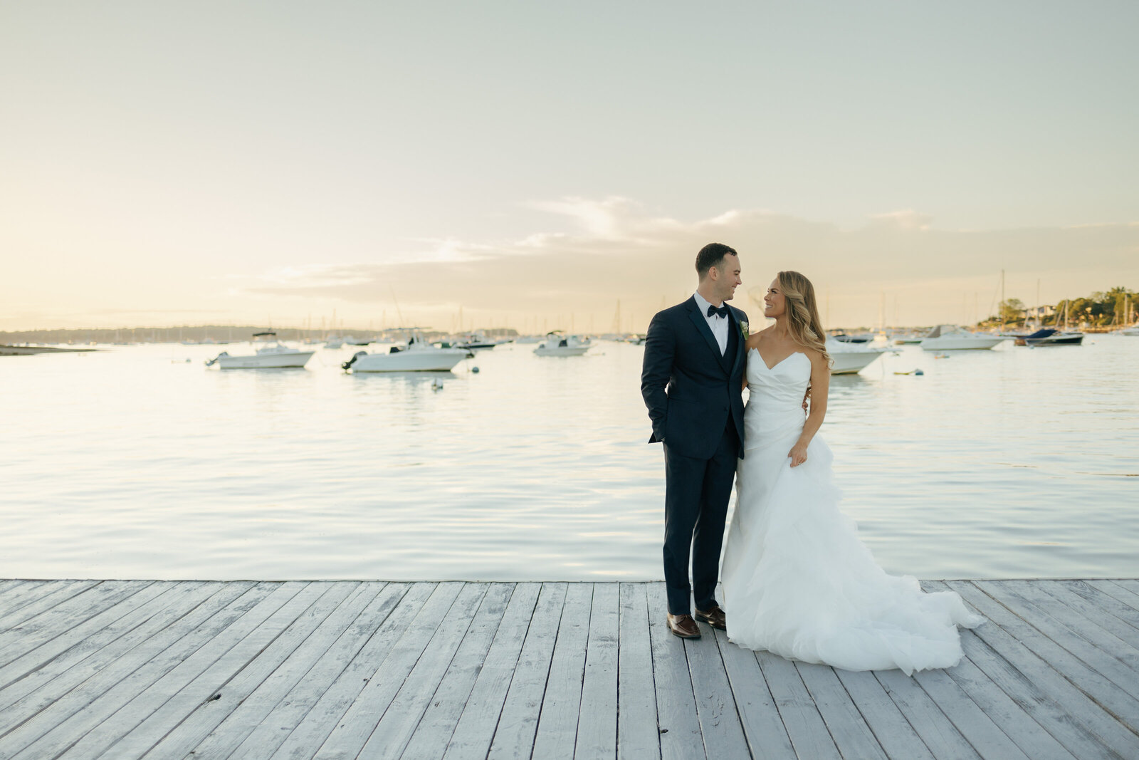 Bride and groom standing side by side on a dock at the waterfront in Suffolk NY | Emma LeeAnn Photography