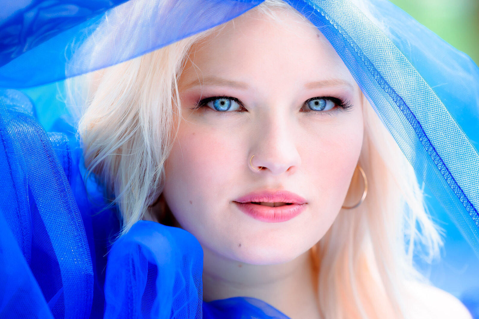 girl with piercing blue eyes and matching blue dress gazes into the camera for a close up