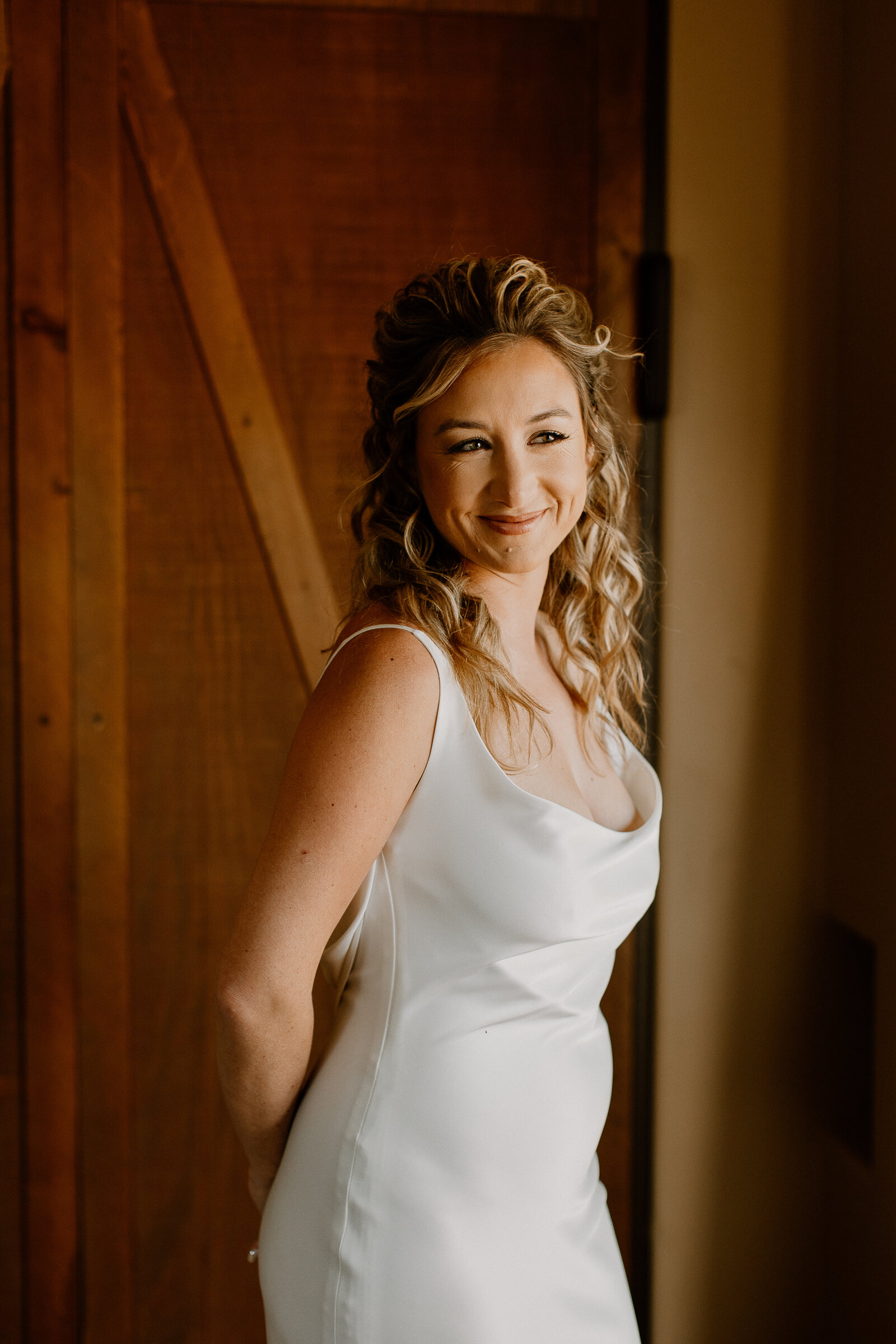 A bride smiling with her hands behind her back.