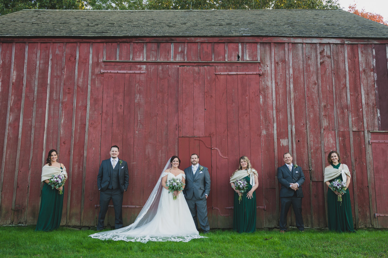 bride and groom with bridal party posing in front of barn at The Barn at Old Bethpage