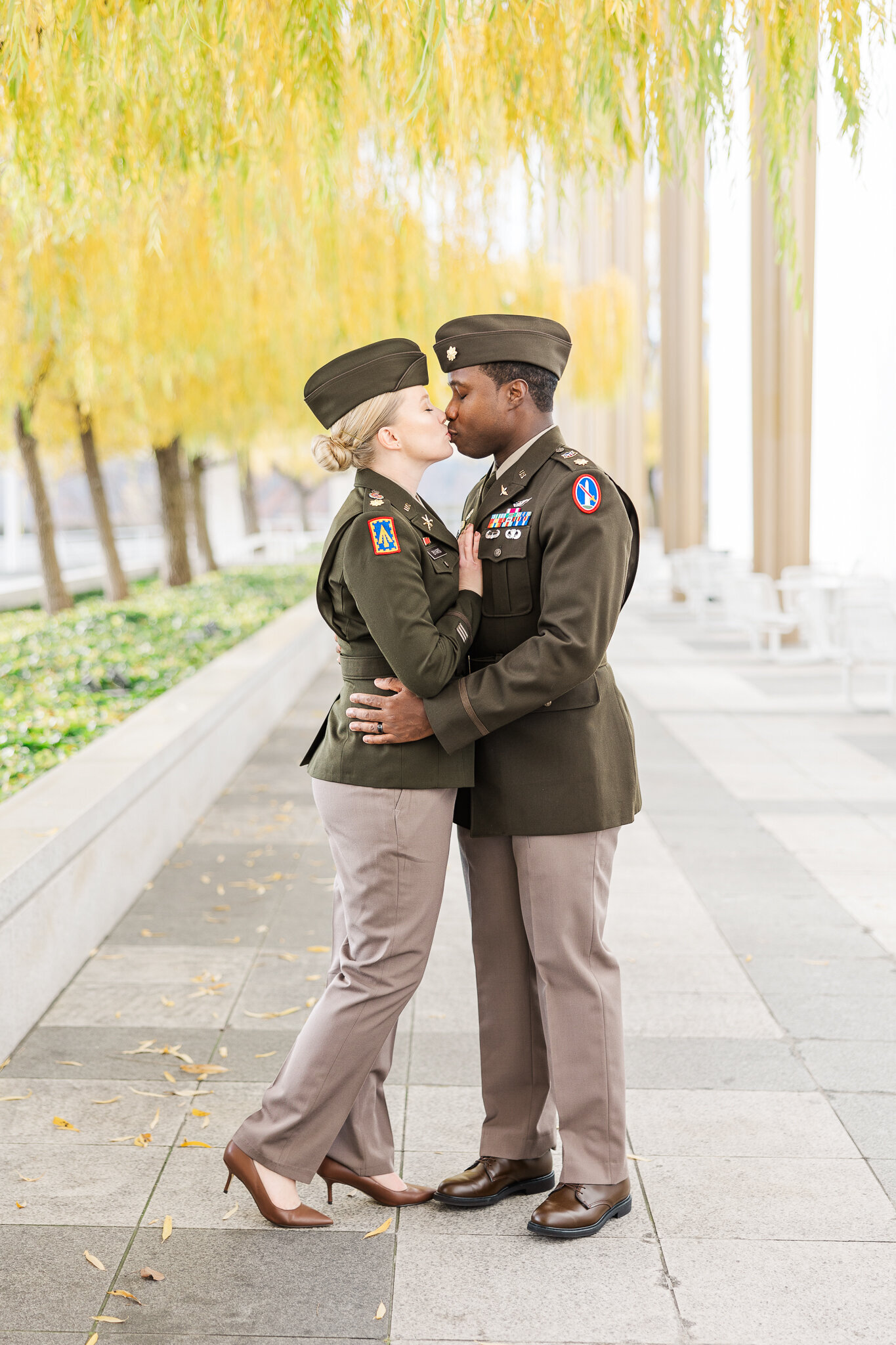 A married couple in Army uniforms kiss at the Kennedy Center in DC