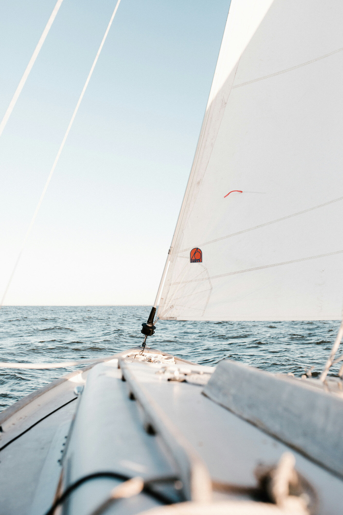 View from the deck of a sailboat looking toward the sail and the open sea