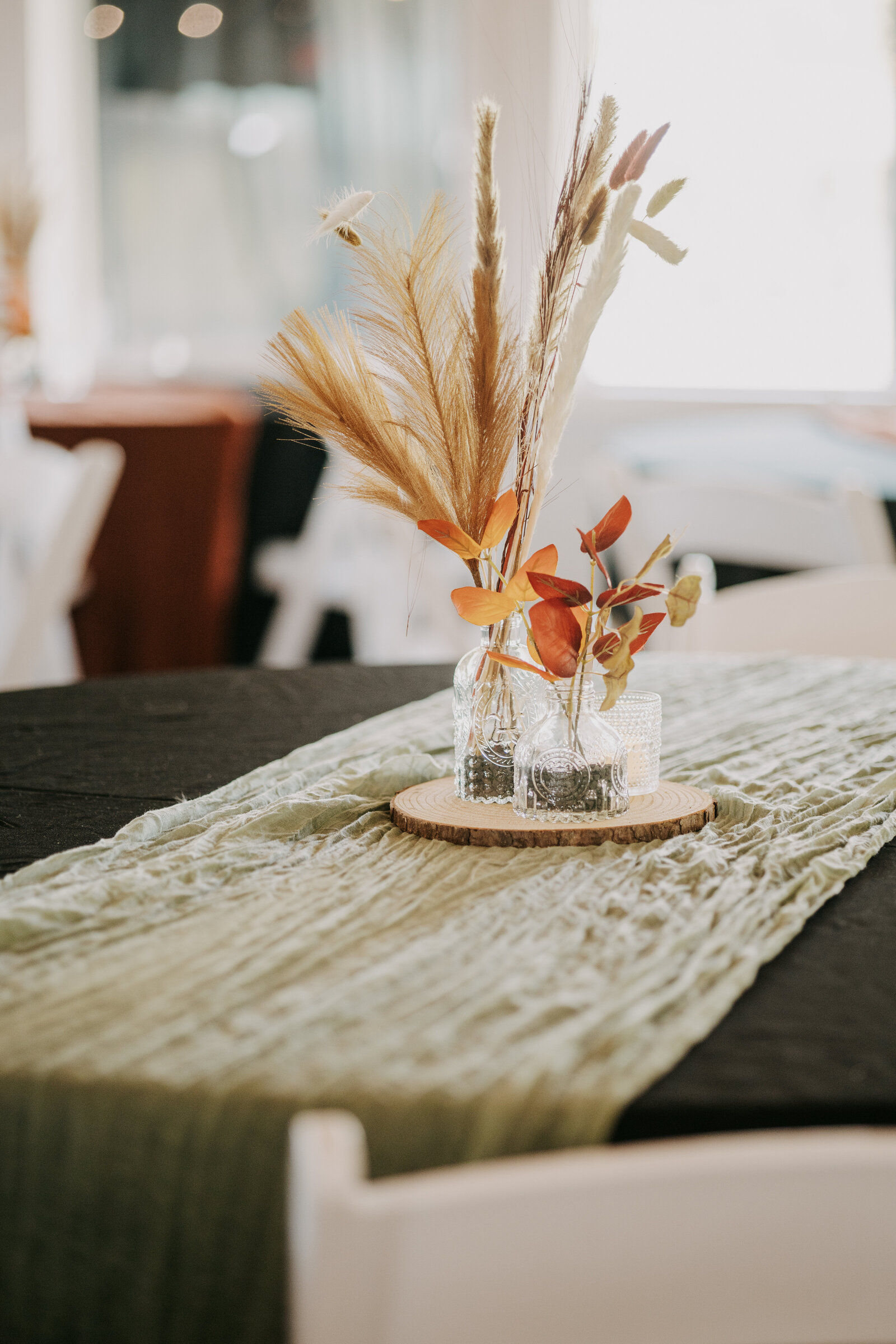 Fall wedding at Navy Lakes in Millington, Tennessee, with a table set up in burnt orange and sage green, featuring flowers in a vase.