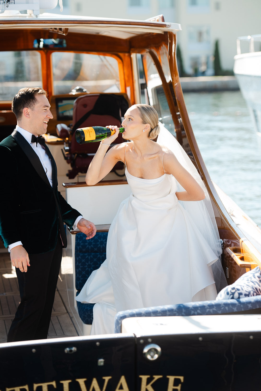 groom with bride chug champagne from bottle on boat